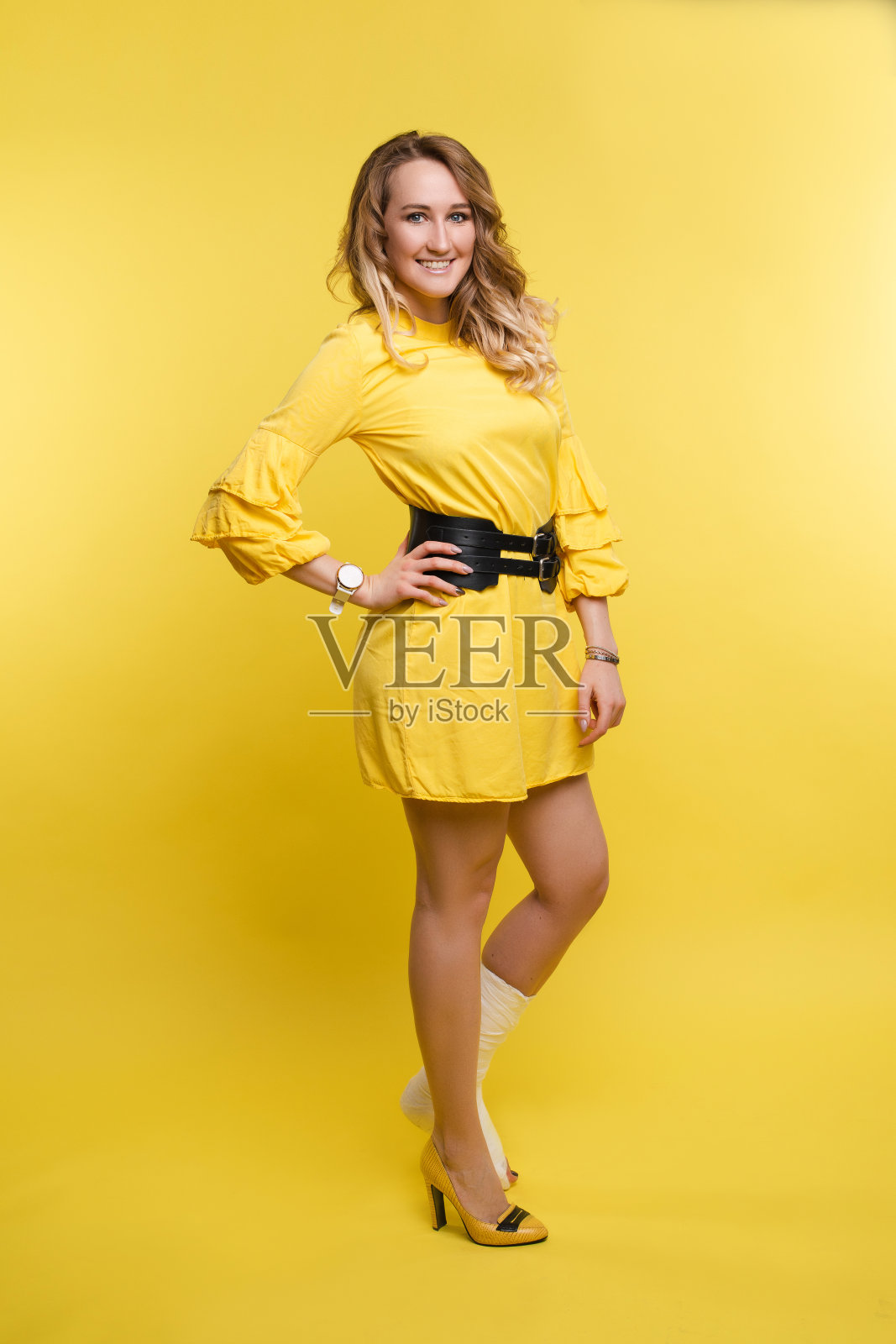 欢快美丽的女人在她的腿上的石膏玩黄色连衣裙。照片摄影图片