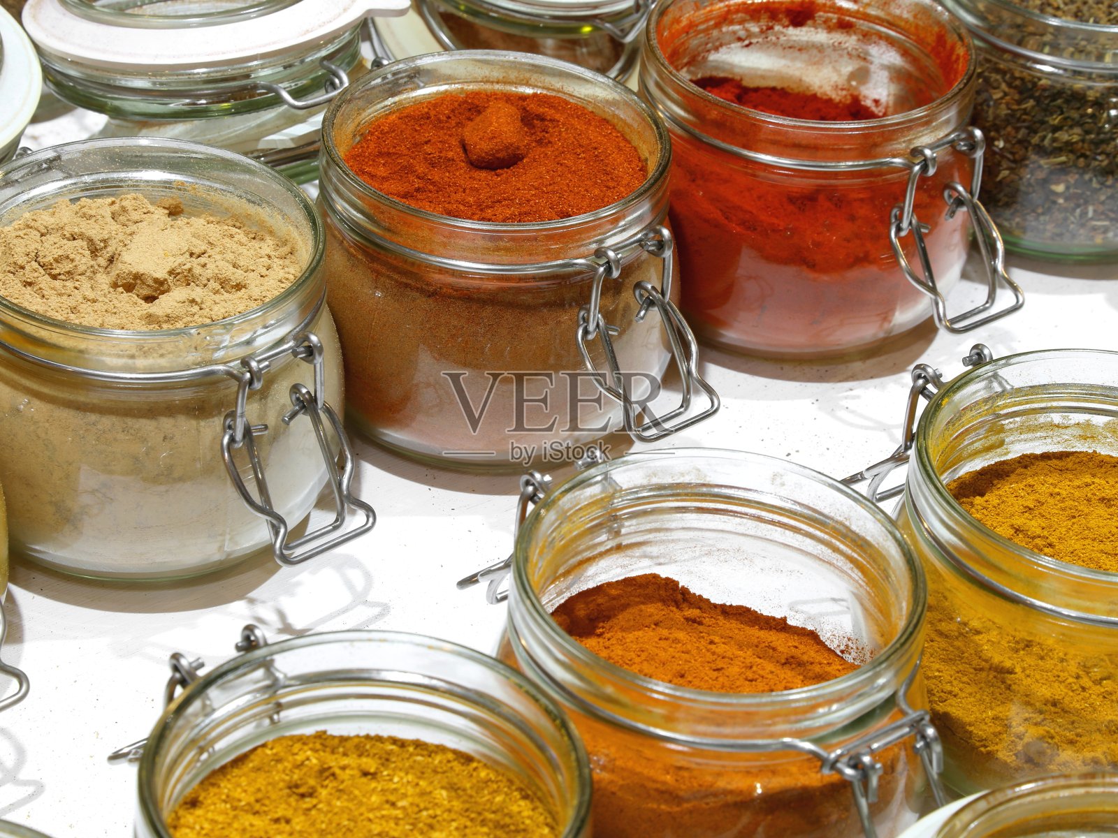 盛有咖喱辣椒、红辣椒、姜黄等东方香料的罐子来给菜肴调味照片摄影图片