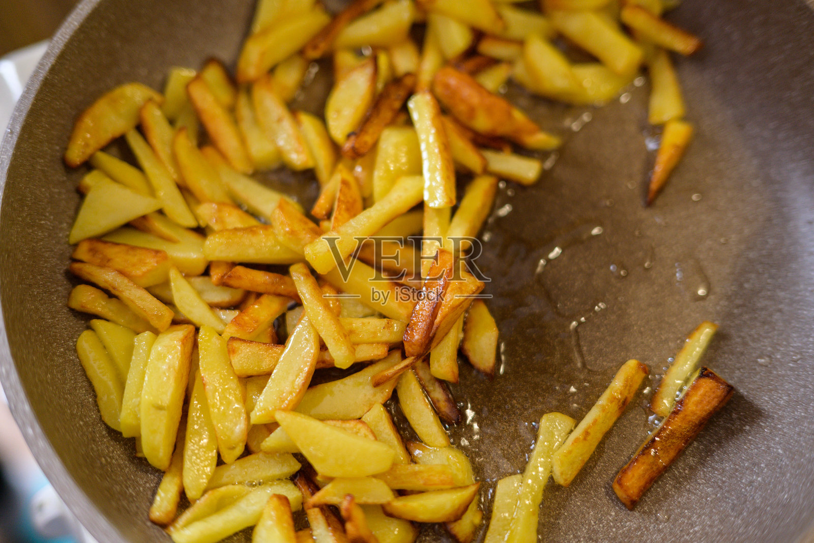 土豆在煎锅里炸。照片摄影图片