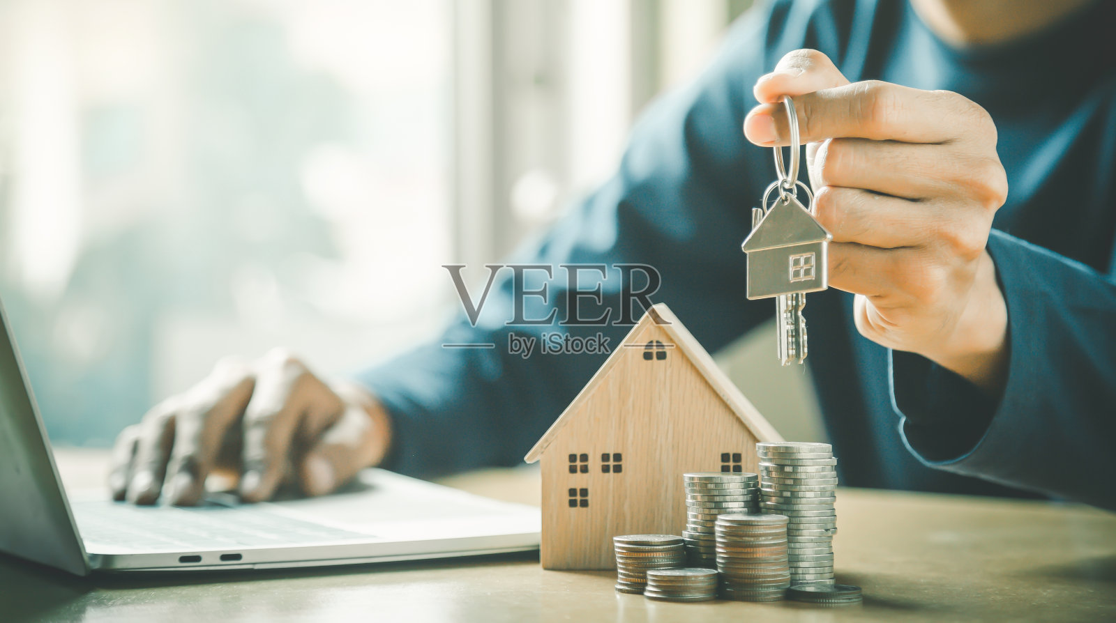 商人从木桌上的模型和钱币的排列中选择迷你木屋模型,选择重点,计划购买房产。选择最好的。象征着建设、生态、贷款的理念。照片摄影图片