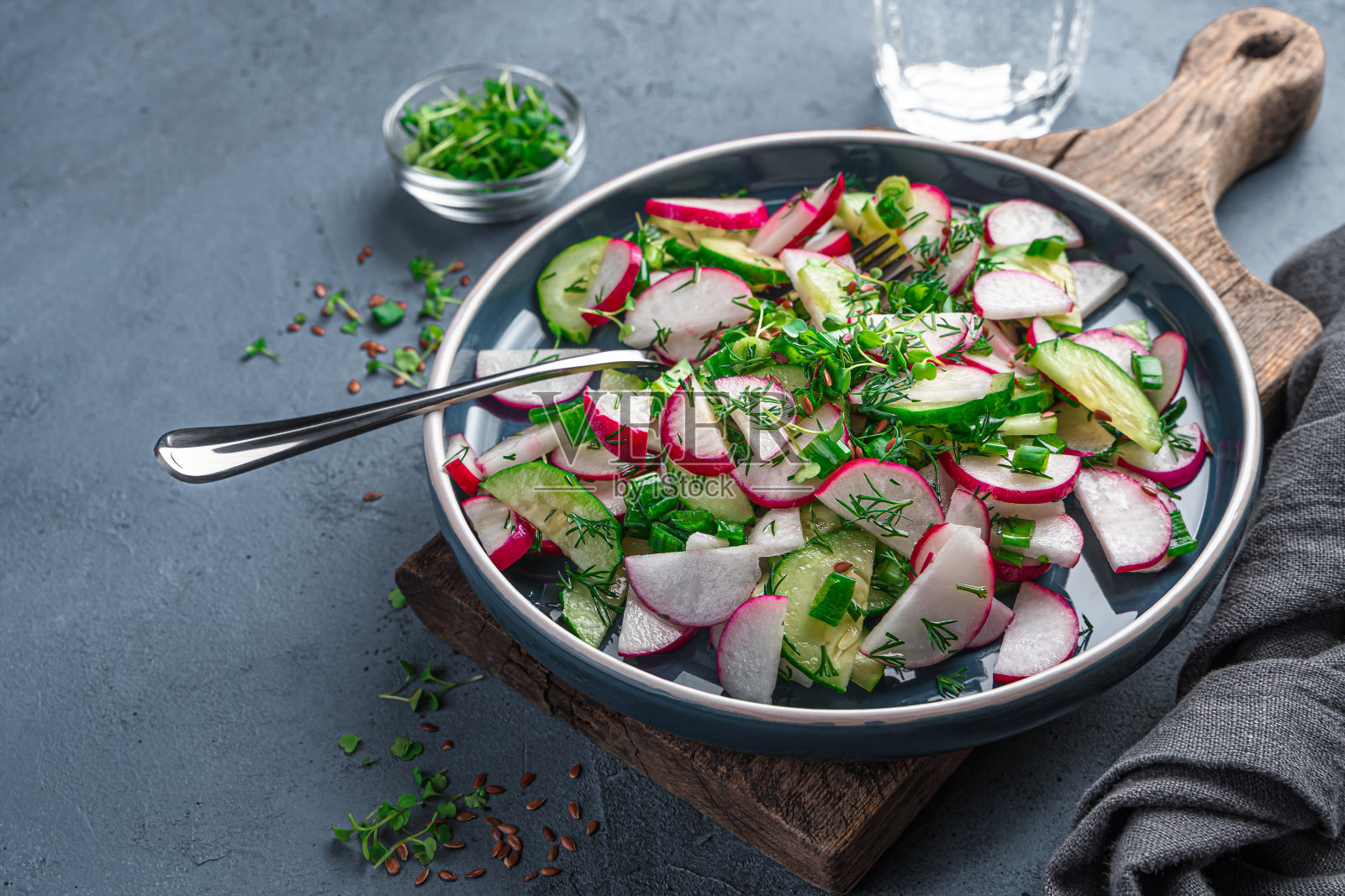 新鲜蔬菜沙拉,萝卜和新鲜香草在石墨背景。照片摄影图片