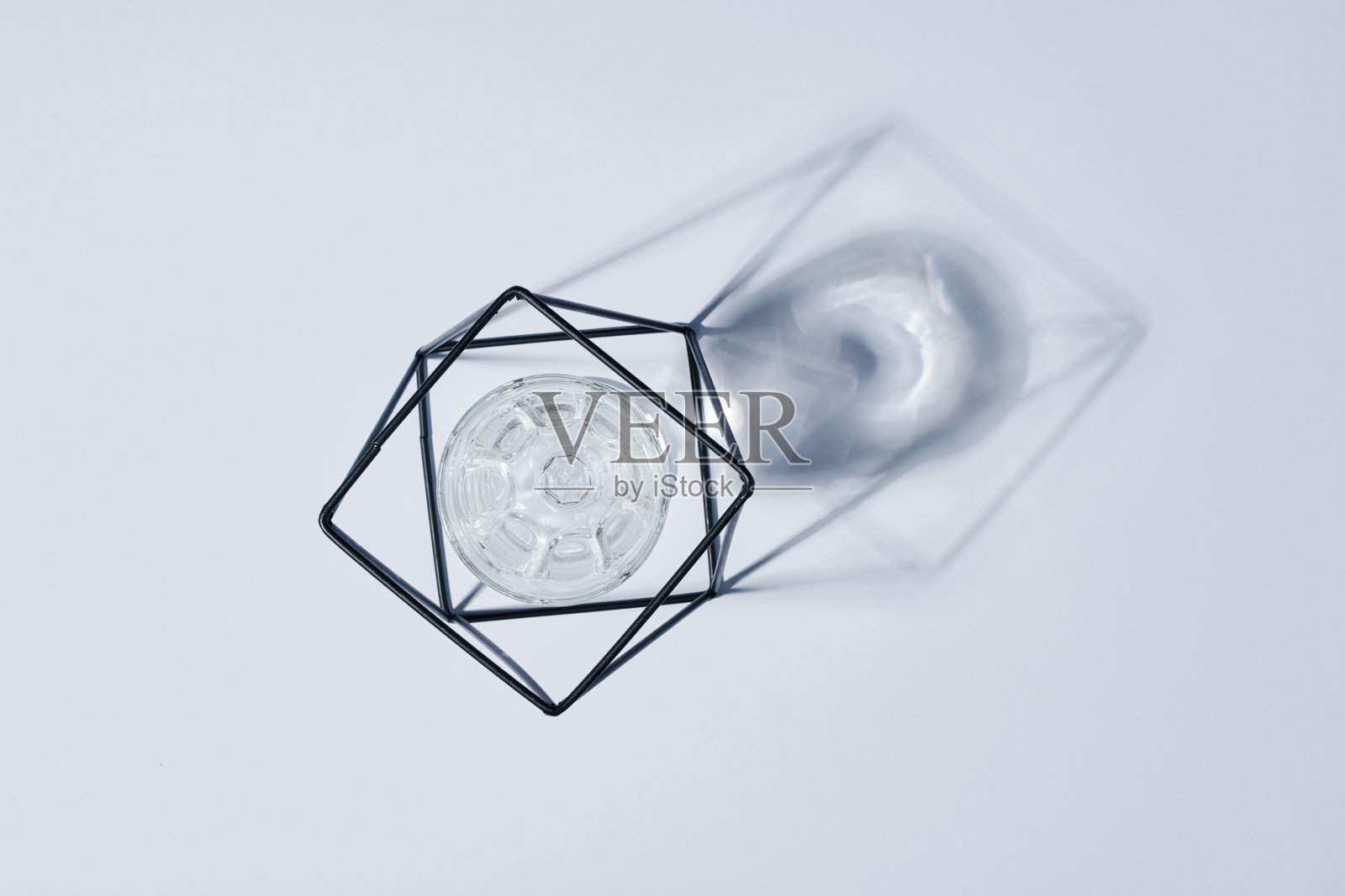 扁平的金属丝手工制作的持有人与玻璃水里面和它的影子照片摄影图片