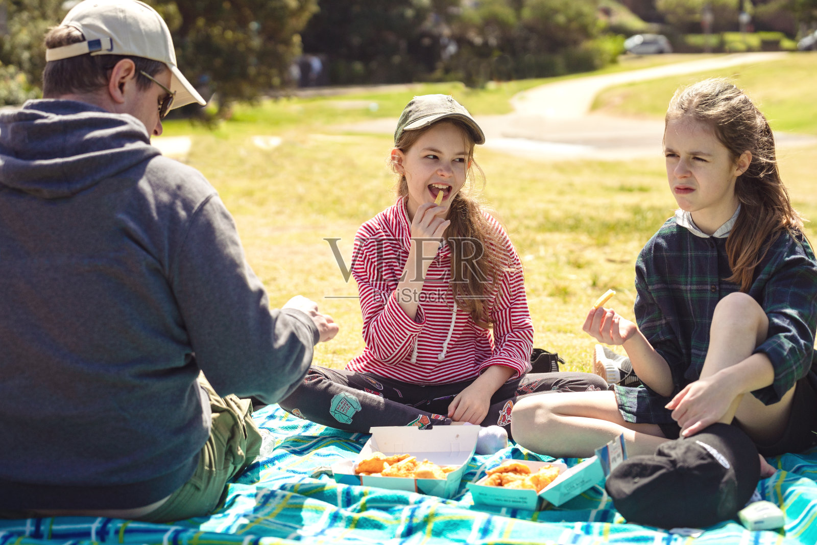 一个阳光明媚的日子,父亲和两个女儿在野餐照片摄影图片