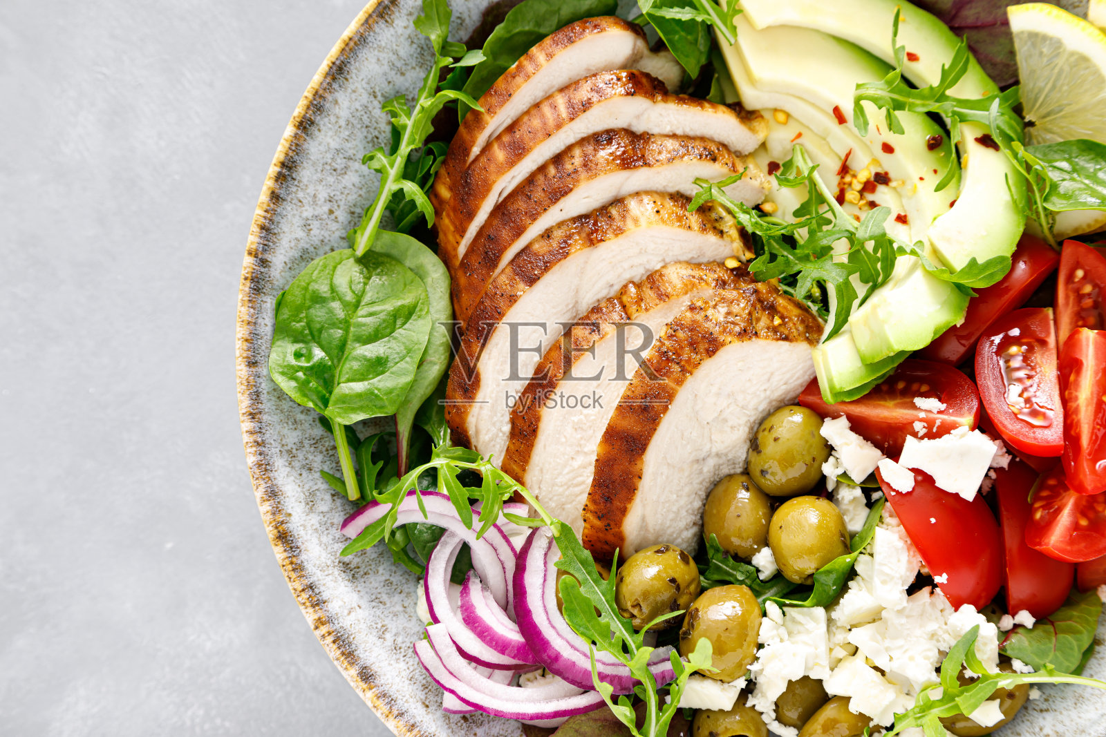 烤鸡胸肉,新鲜蔬菜沙拉,番茄,羊乳酪,橄榄和鳄梨。健康食品。俯视图照片摄影图片