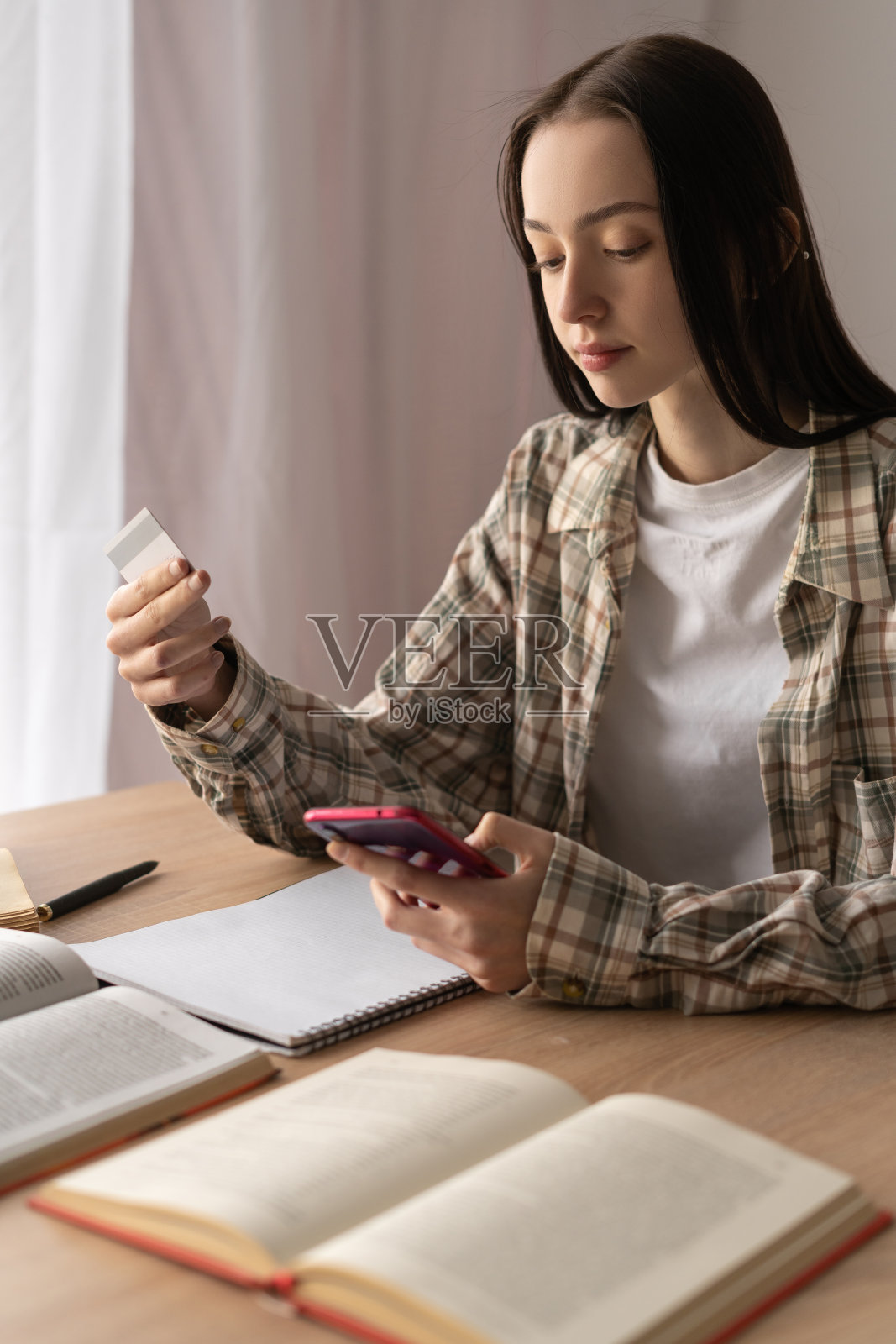 垂直视图,年轻的女学生使用信用卡和智能手机在线购物,在线支付,无现金支付照片摄影图片