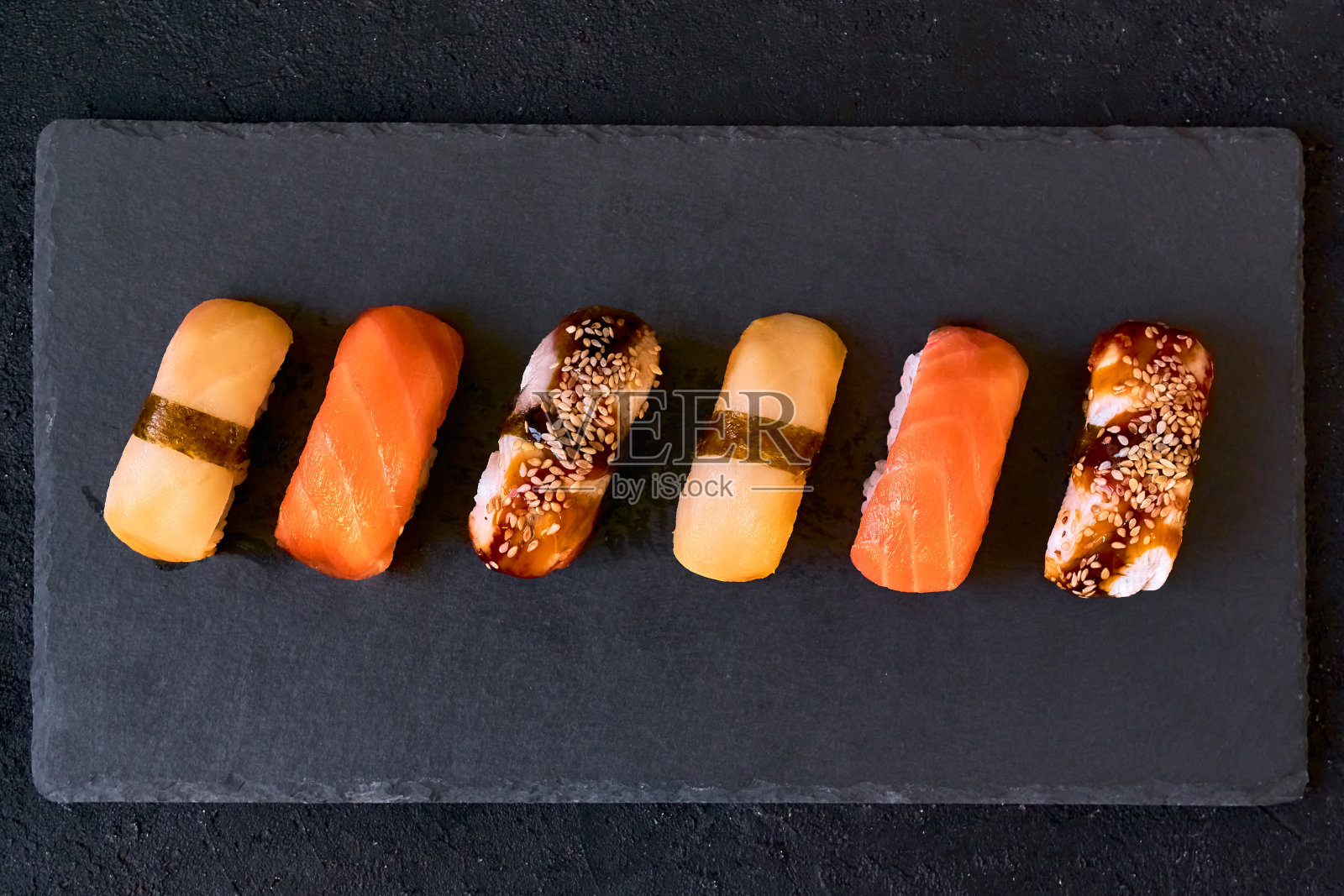 搭配三文鱼,鳗鱼,鳗鱼寿司,黑色石板,黑色背景。最小的概念。照片摄影图片