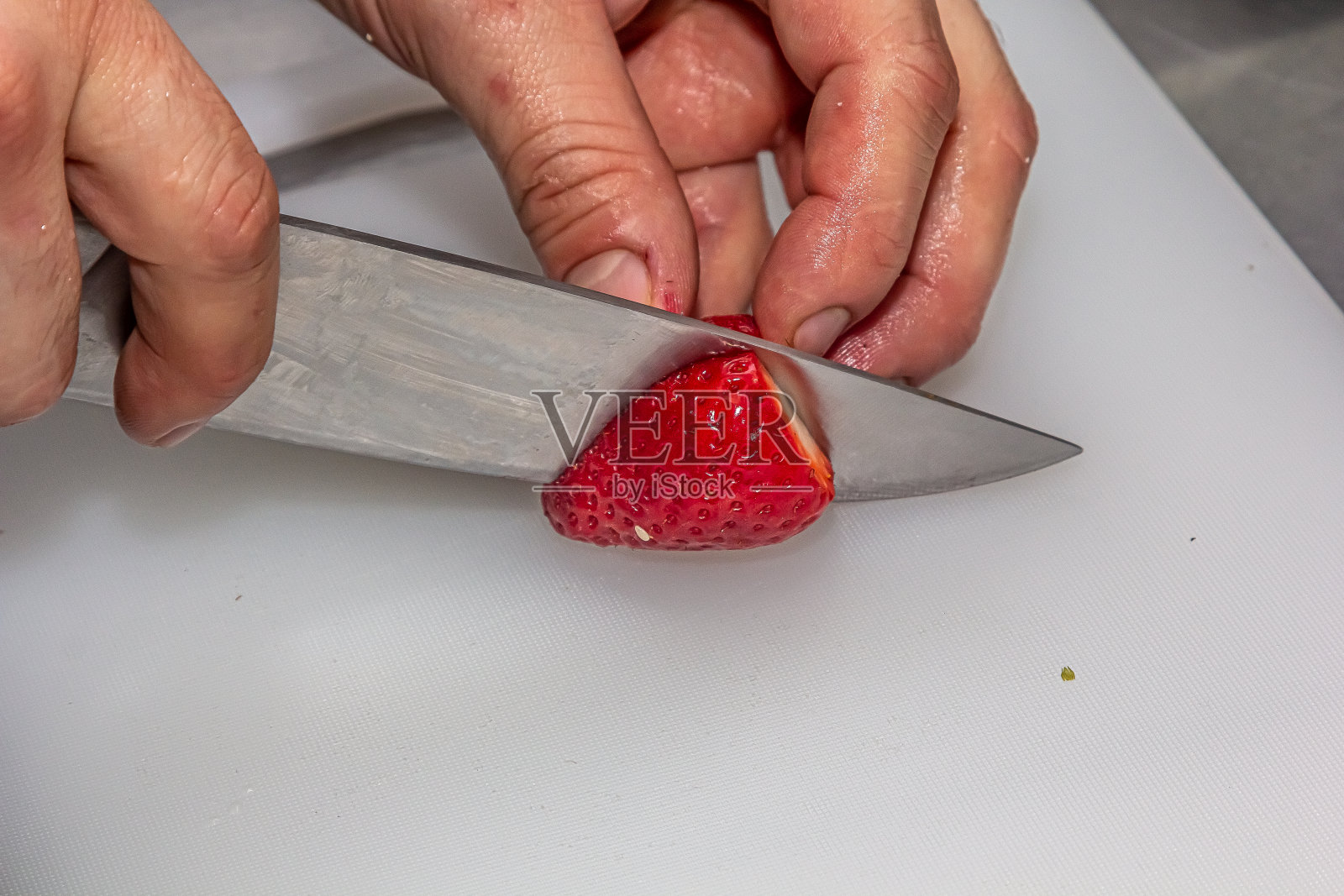 特写厨师在餐厅厨房的砧板上切新鲜草莓,用来制作薄荷饮料。烹饪饮食甜点照片摄影图片
