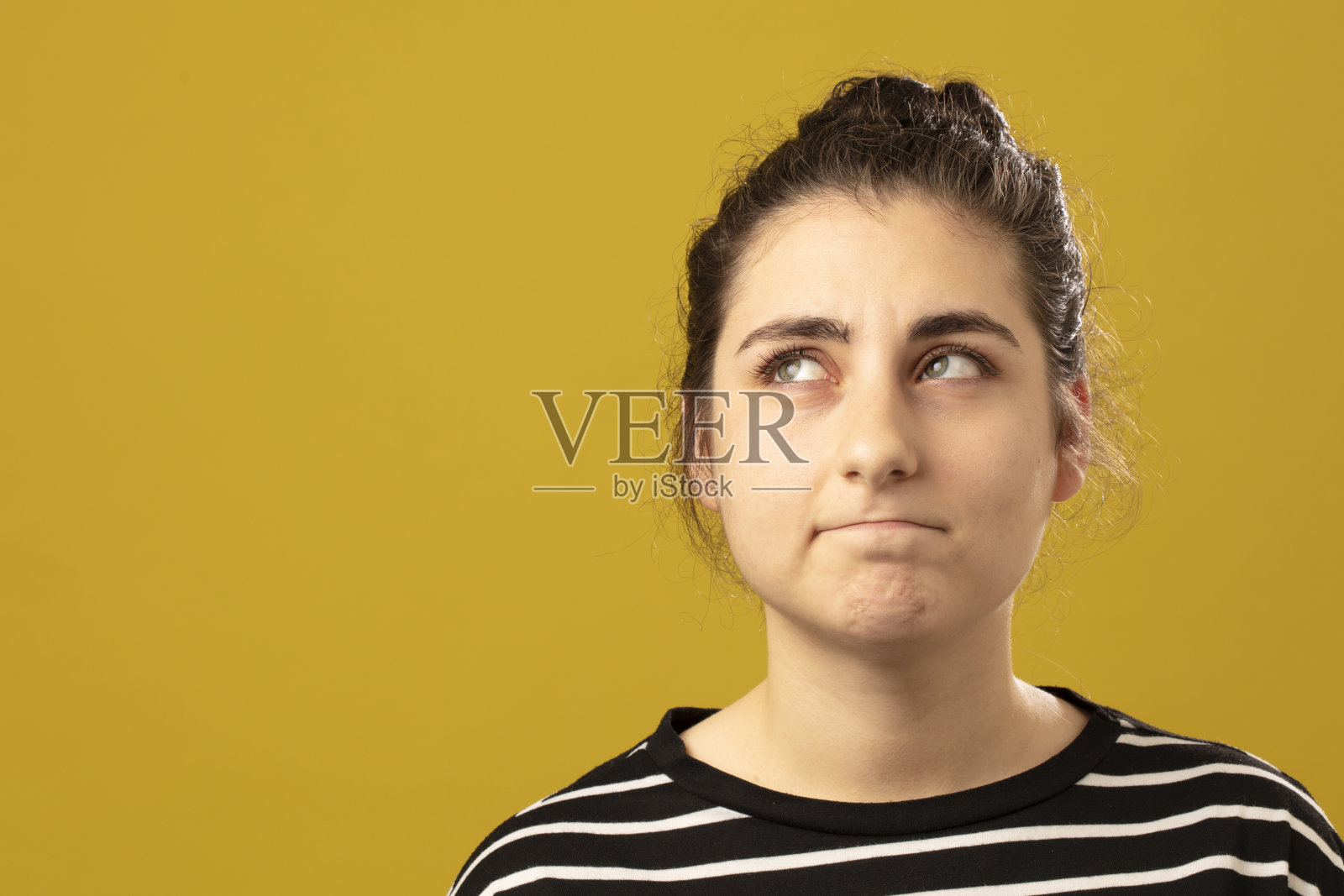 照片肖像严重和担心的女孩穿着条纹t恤孤立的黄色背景照片摄影图片
