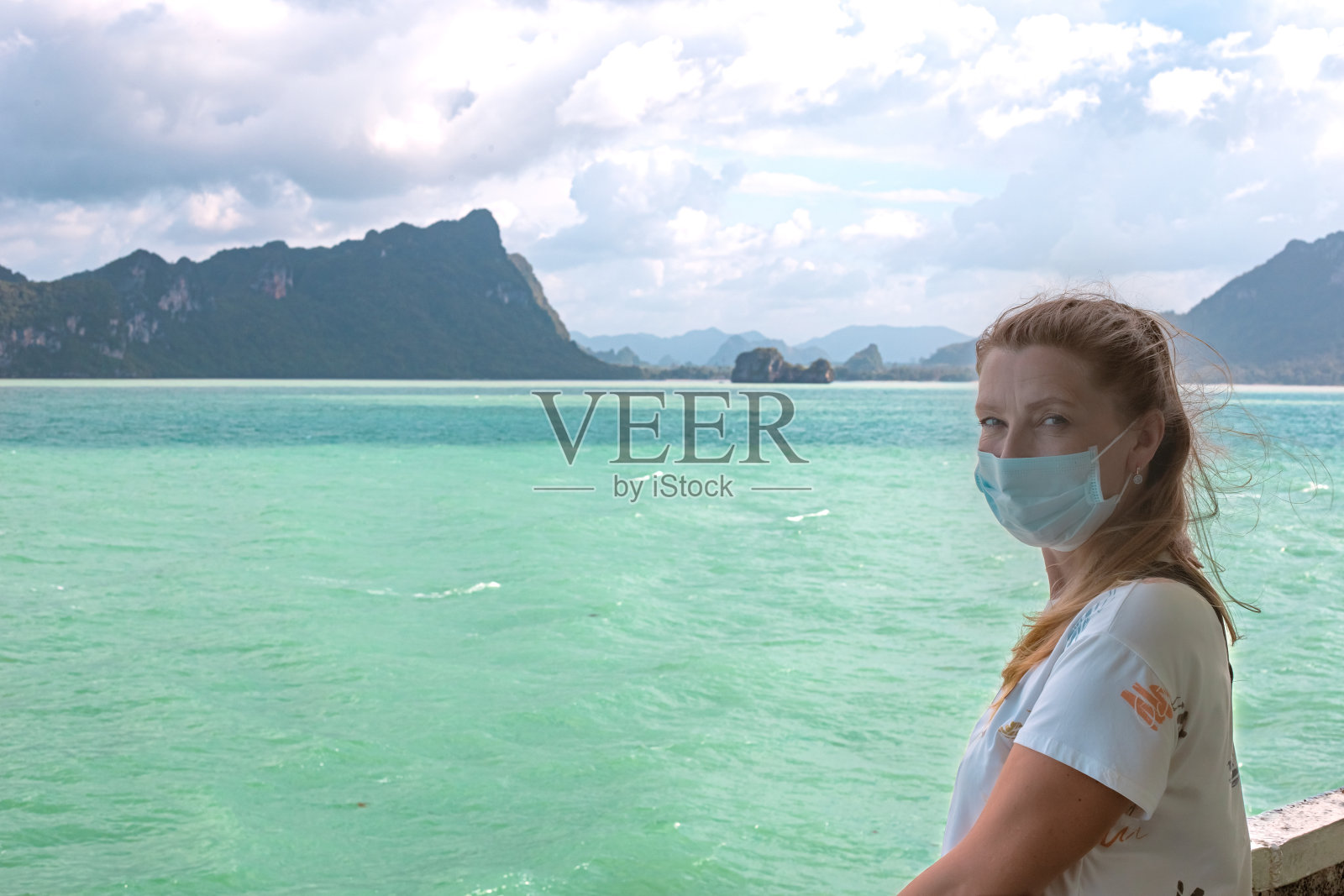 戴着口罩的女子乘坐的渡轮,漂浮在美丽的岛屿和群山之间的海上。旅行和旅游照片摄影图片