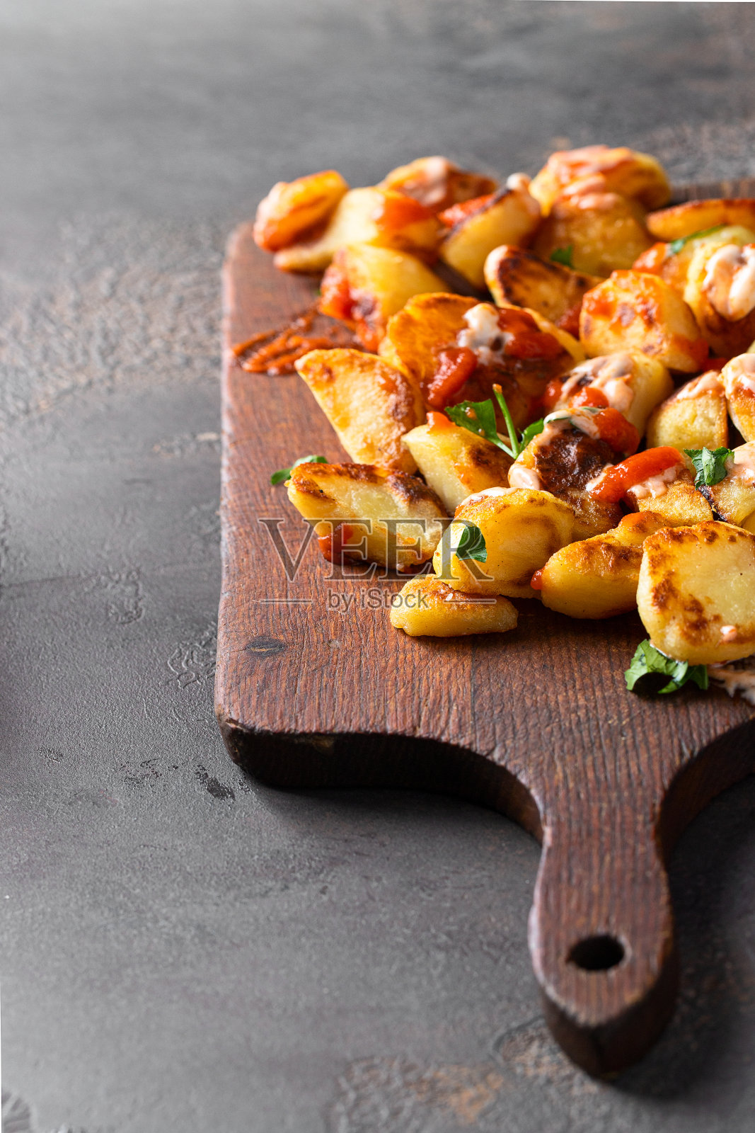 流行的西班牙餐前小吃,在木制切菜板上的马铃薯和番茄酱和蒜泥蛋黄酱照片摄影图片