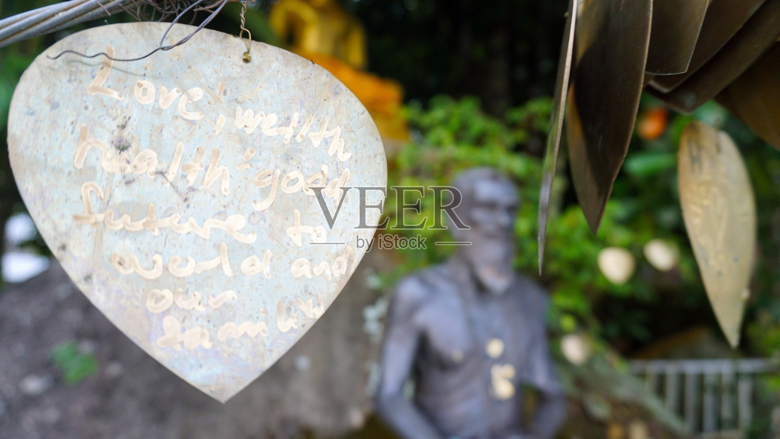 带着愿望的金属心挂在花园里照片摄影图片