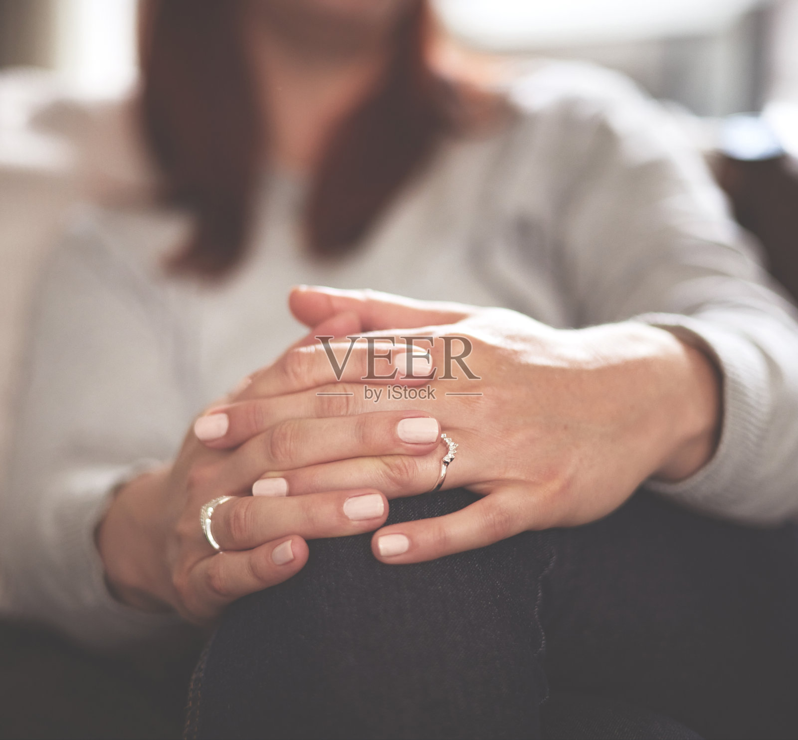 一个女人双手合十的特写。一个陌生的女人在等待,坐在家里的沙发上,或者在咨询师那里接受治疗照片摄影图片