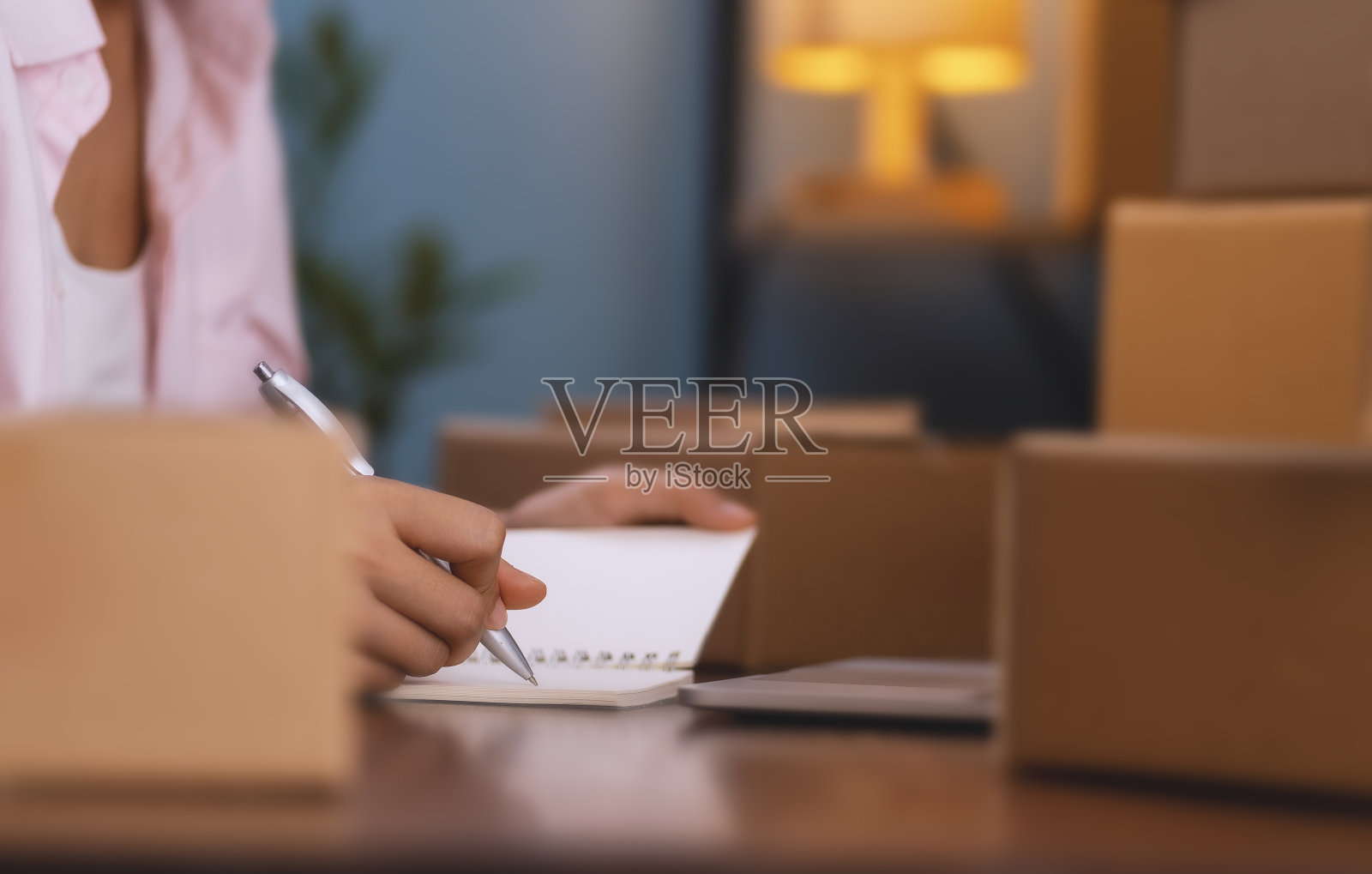 在网上销售产品。一名年轻女子正在打包产品,准备发给网上的顾客。照片摄影图片