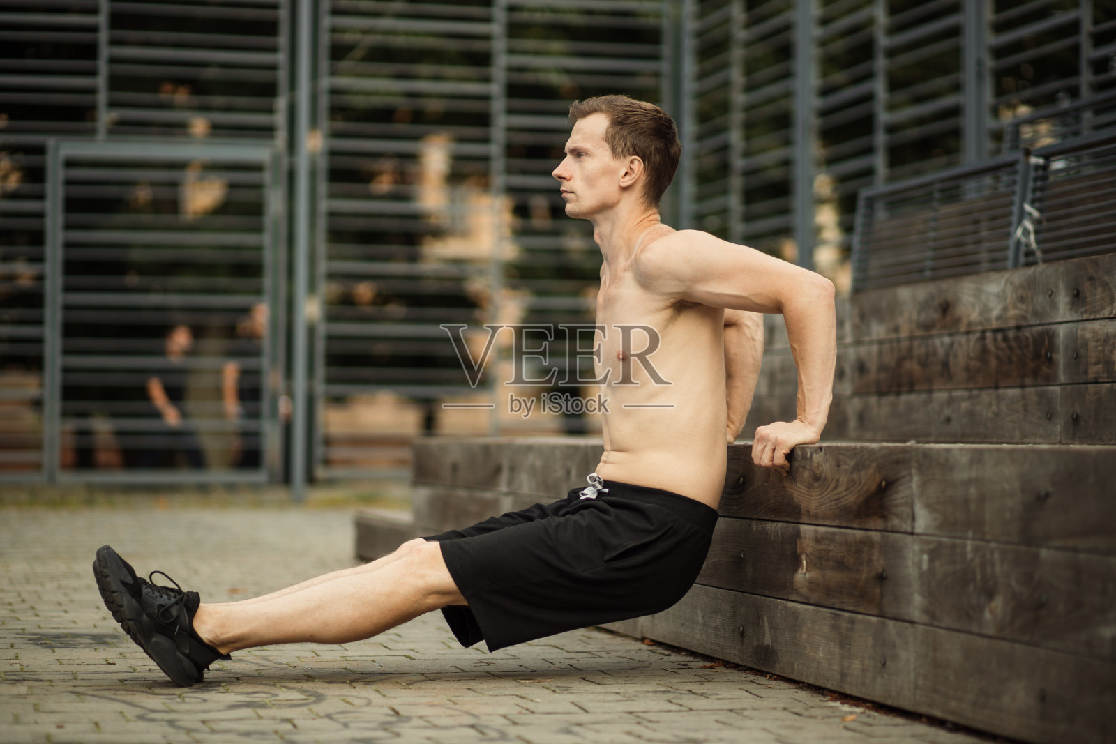 一个专注的肌肉男的肖像,穿着黑色运动服做跳水,训练手臂肌肉照片摄影图片