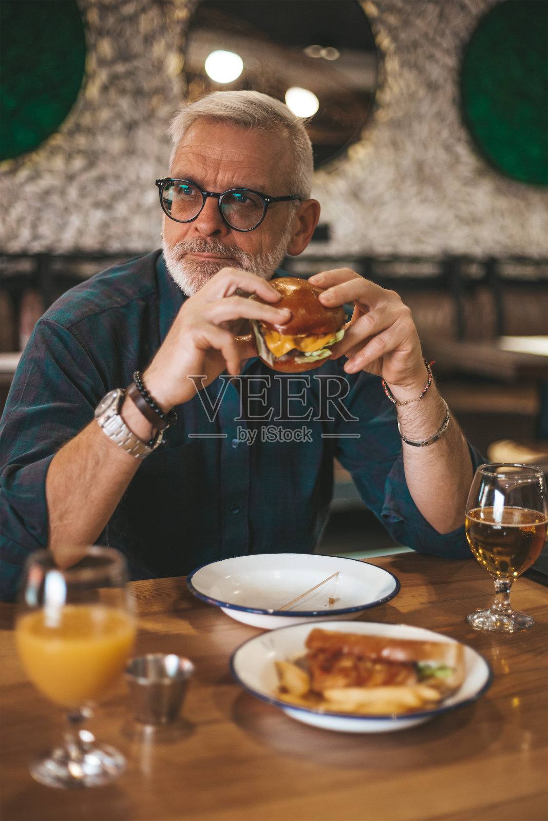 高级男子在餐厅吃汉堡,午休时间。照片摄影图片