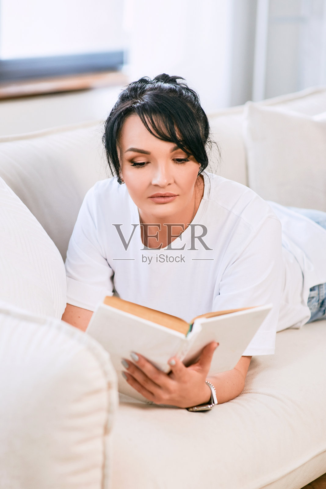 美女在沙发上看书。自由时间,教育,自我发展理念。照片摄影图片