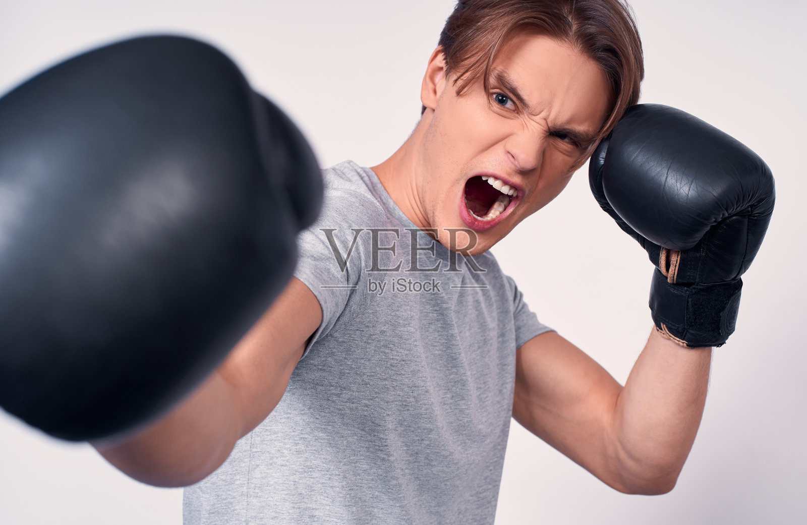 在白色背景下呐喊的年轻拳击手照片摄影图片