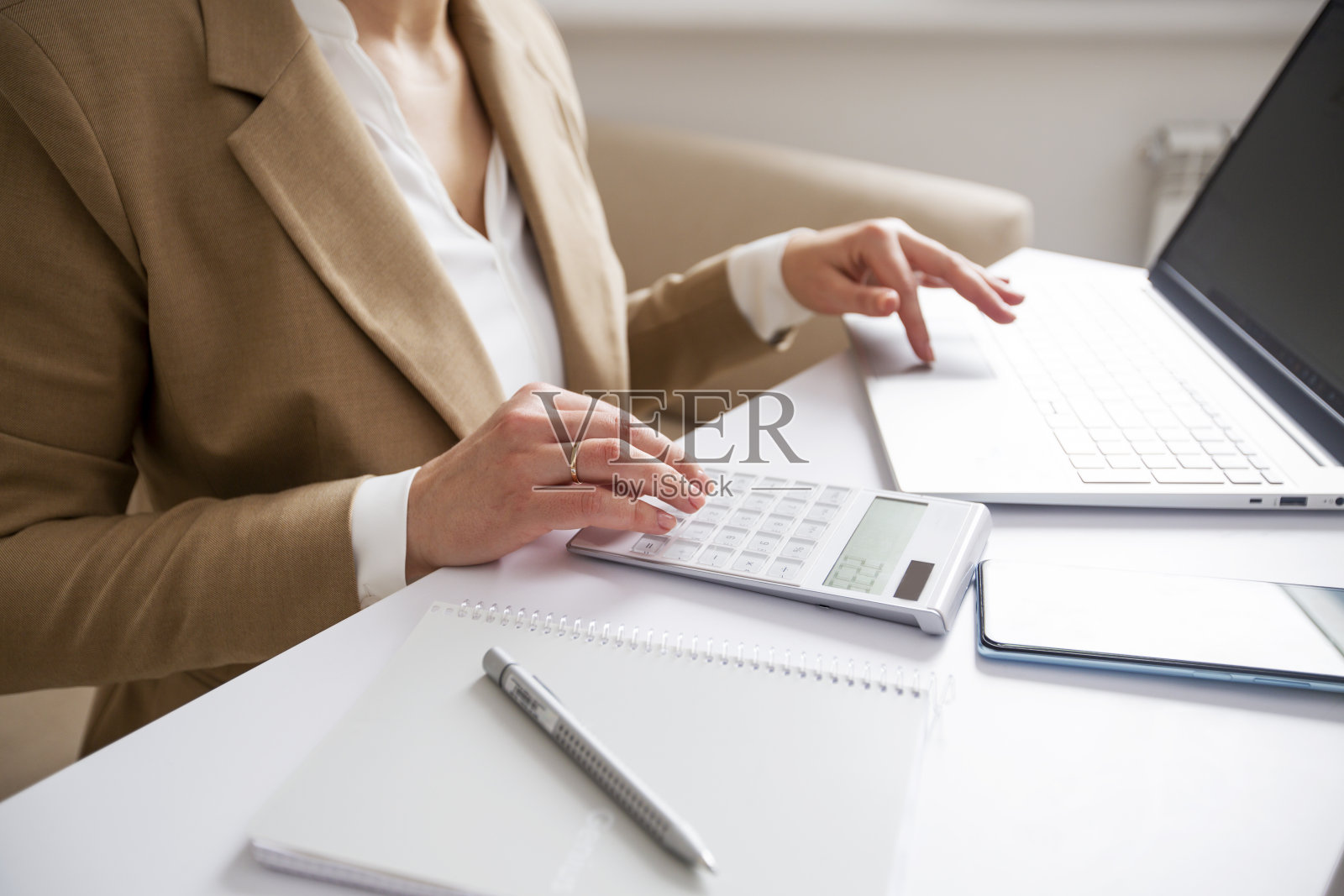 一位女商人用计算器计算预算或金钱,并使用笔记本电脑工作照片摄影图片