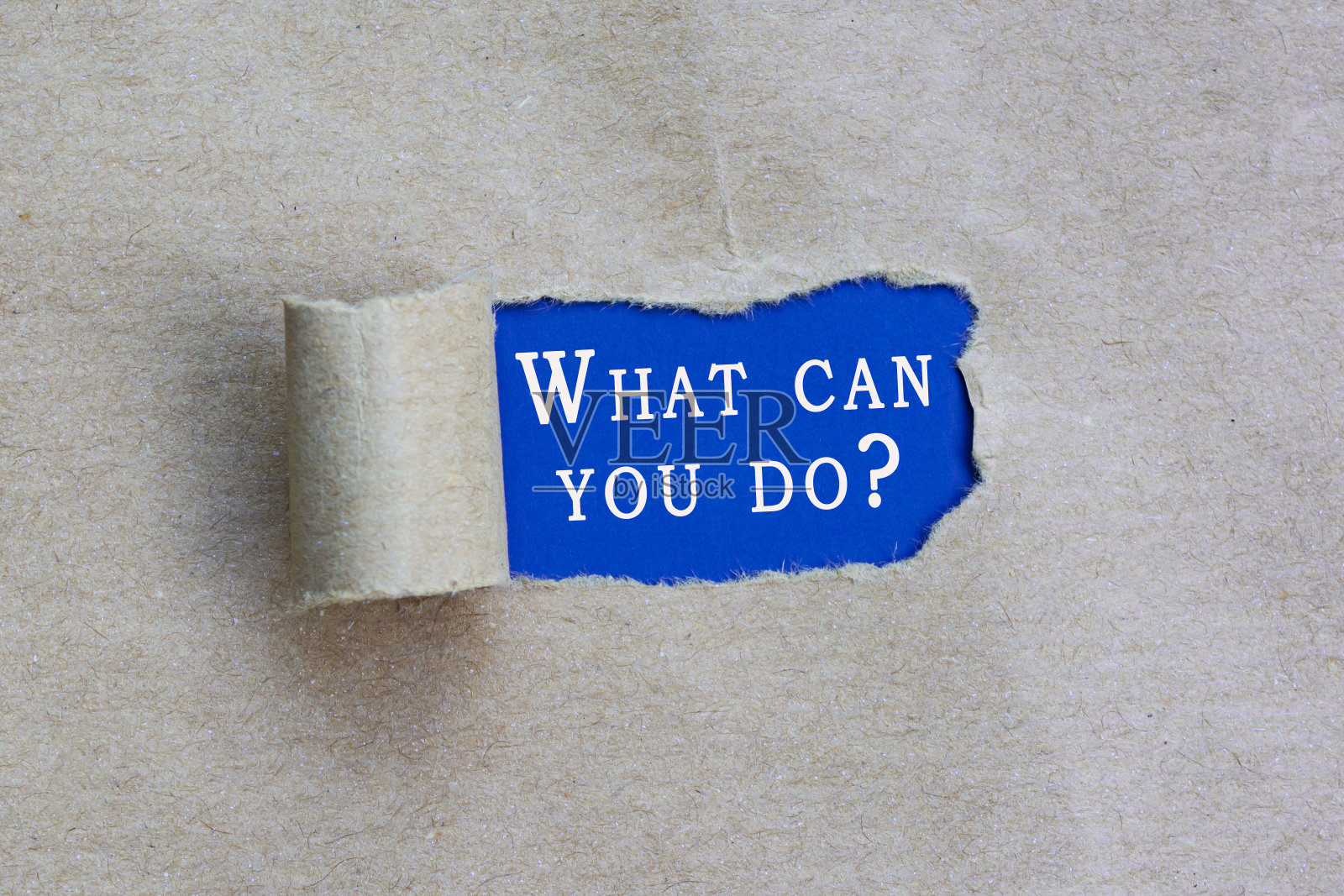 你能做什么?文字在蓝色背景的牛皮纸上撕破了一个洞照片摄影图片