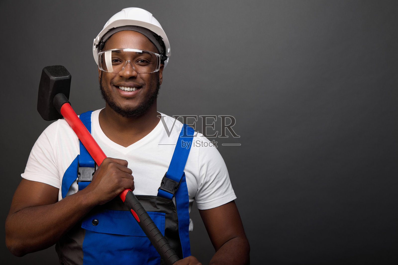 一个强壮的黑人工人拿着一把红色柄的大锤照片摄影图片