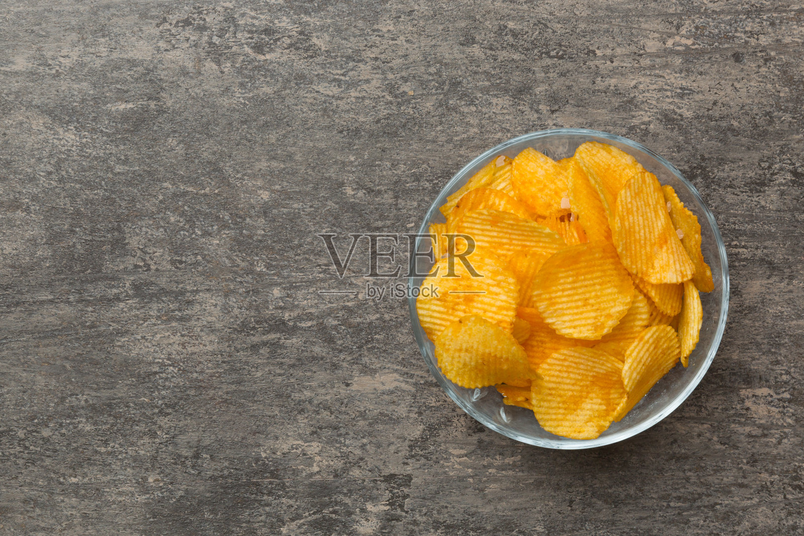 土豆片在碗上隔离的彩色背景。碗里的美味脆薯片。空间的文本。俯视图照片摄影图片