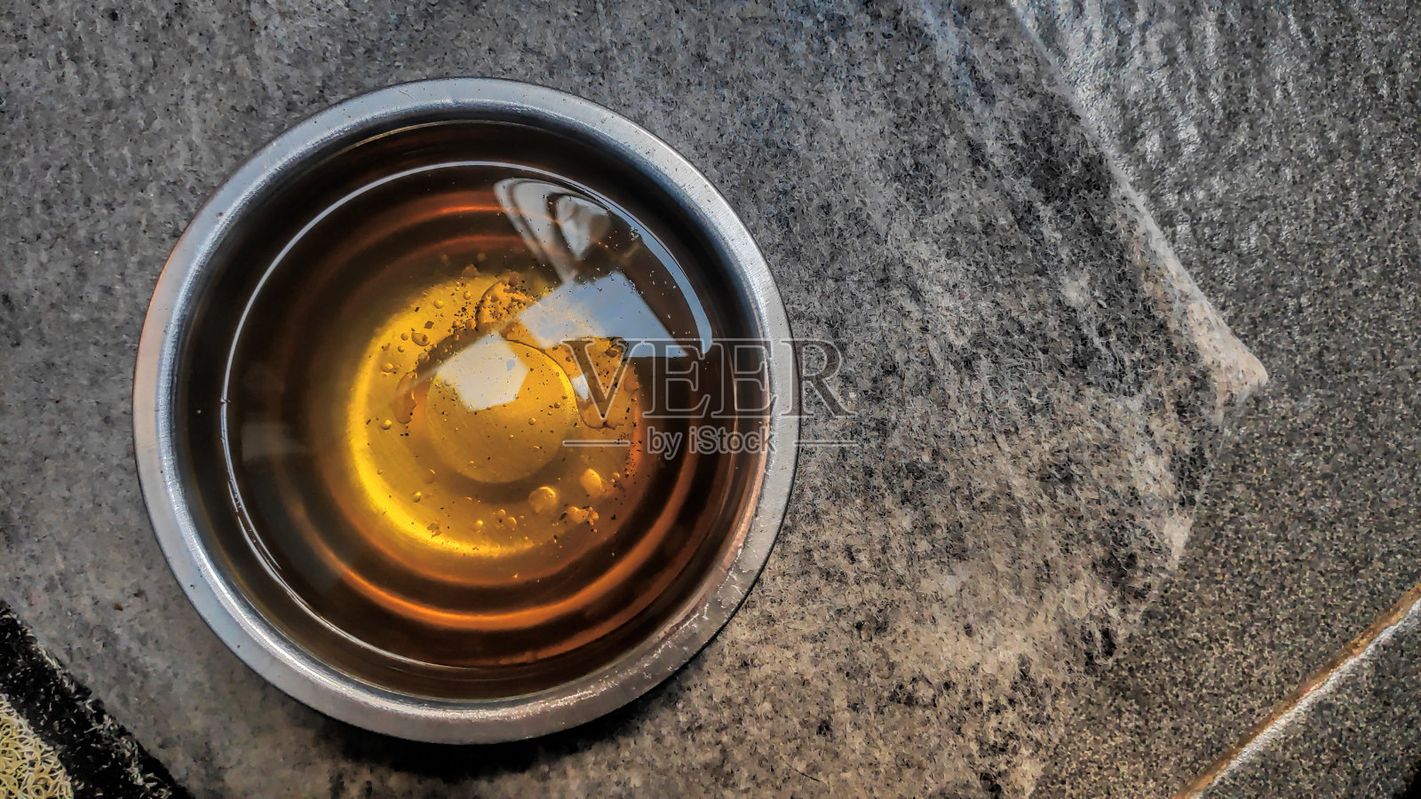 植物油在一个清晰的金属碗在木材背景照片摄影图片