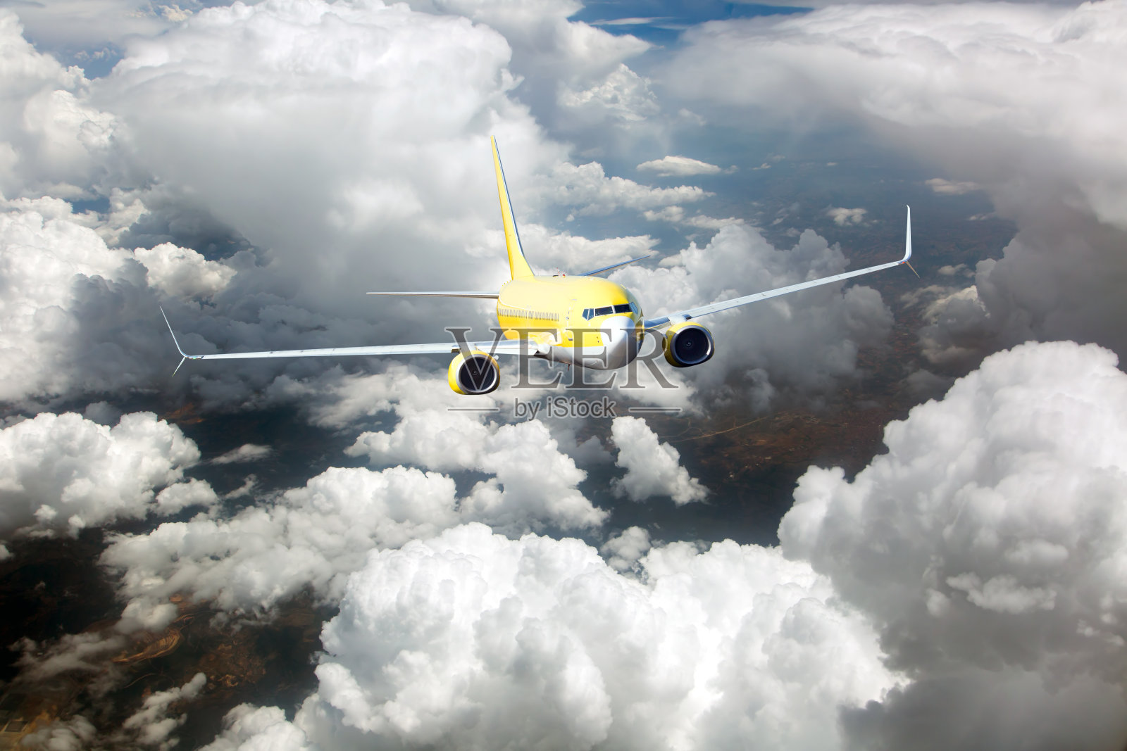 黄色客机飞越云层。飞机前视图。照片摄影图片