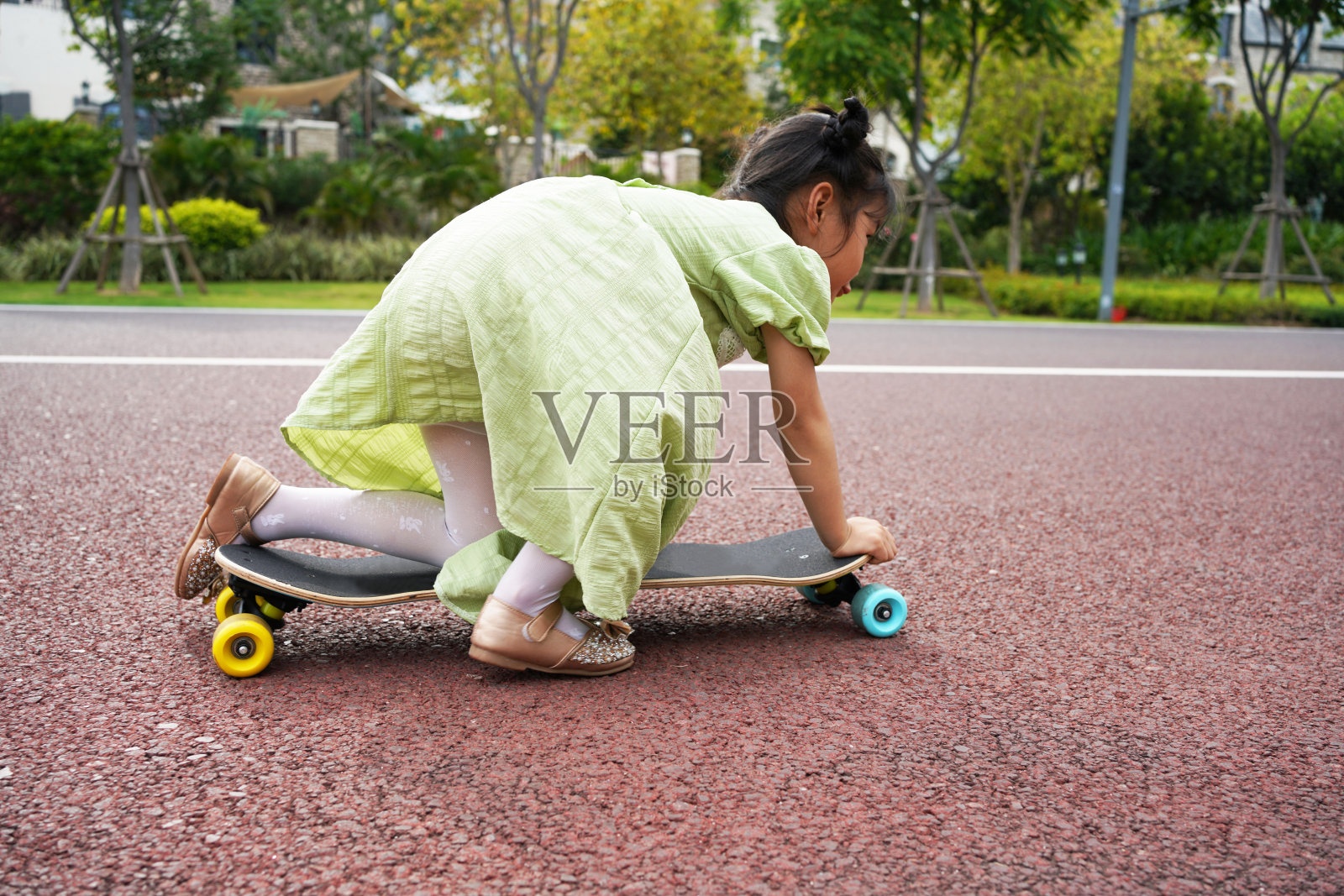 这个小女孩跪下来学滑板照片摄影图片
