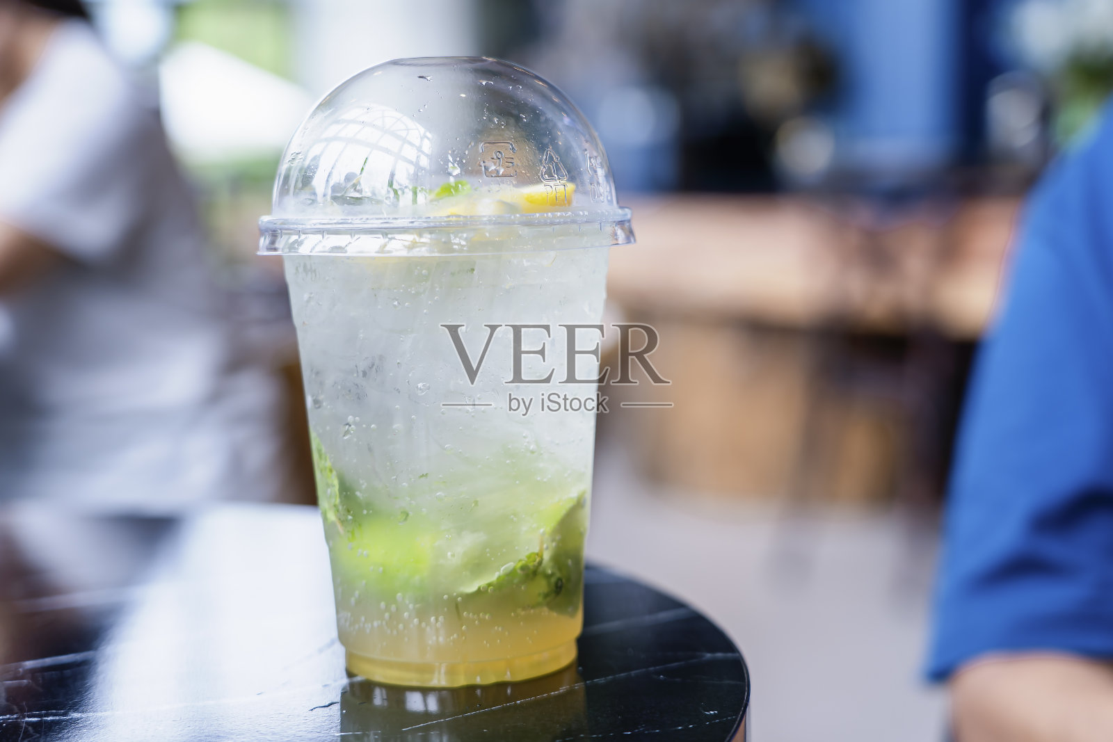 夏日清爽饮品,冰柠檬汁配新鲜柠檬片。柠檬汁鸡尾酒在桌子上与模糊的吧台背景在咖啡馆的副本空间。假日健康饮料理念照片摄影图片