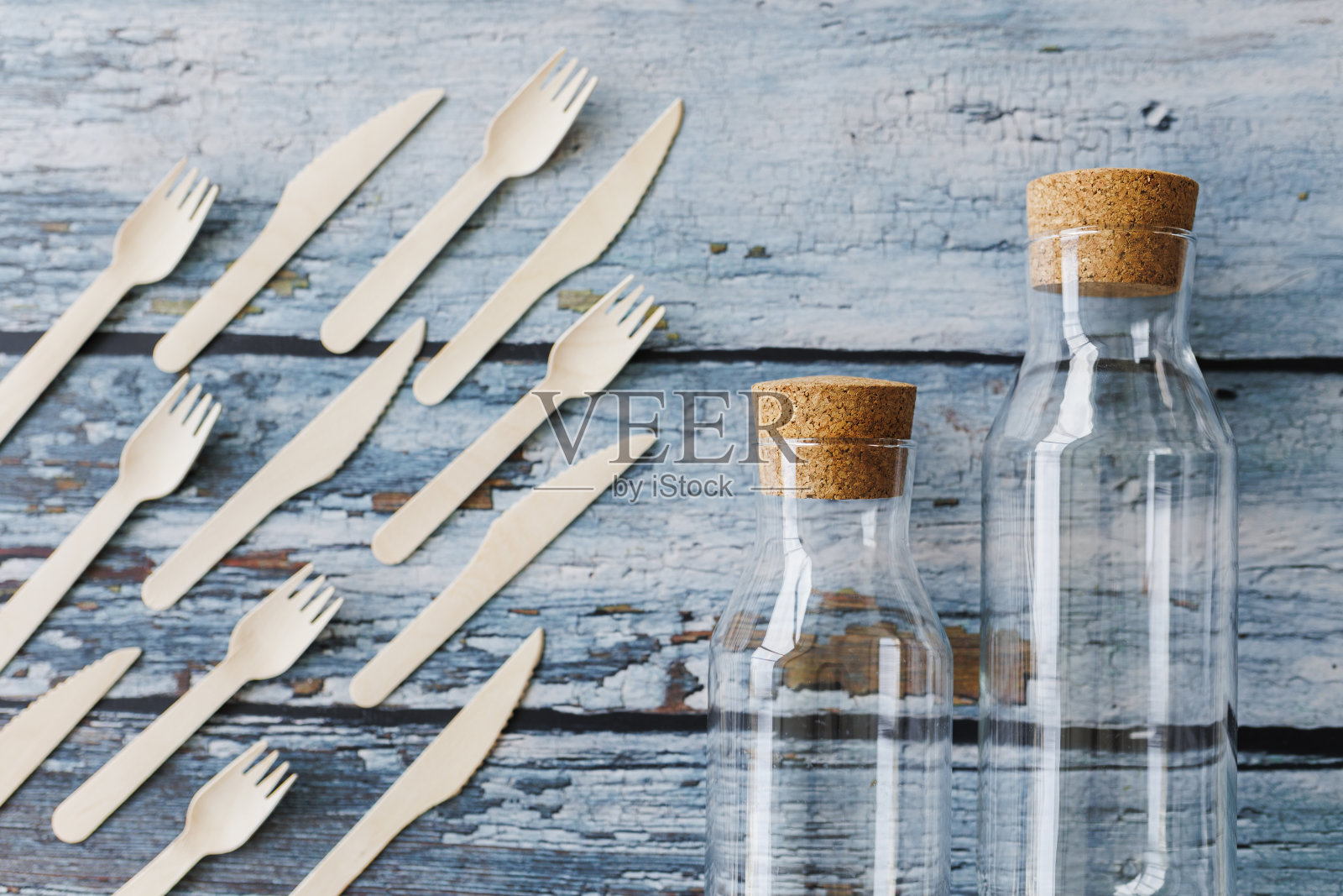 浅蓝色木制背景上的环保餐具平面组合。牛皮纸盘子和木制餐具。可回收的纸制品,零浪费的理念。有选择性的重点照片摄影图片