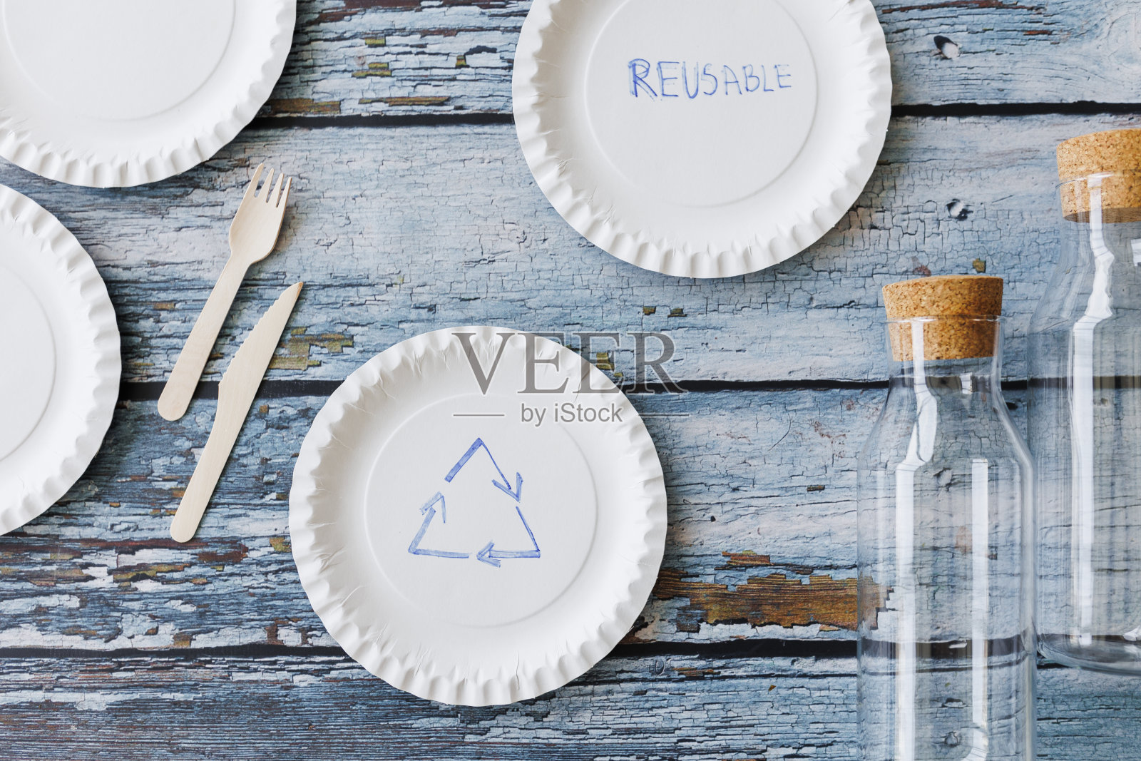 浅蓝色木制背景上的环保餐具平面组合。牛皮纸盘子和木制餐具。可回收的纸制品,零浪费的理念。有选择性的重点照片摄影图片