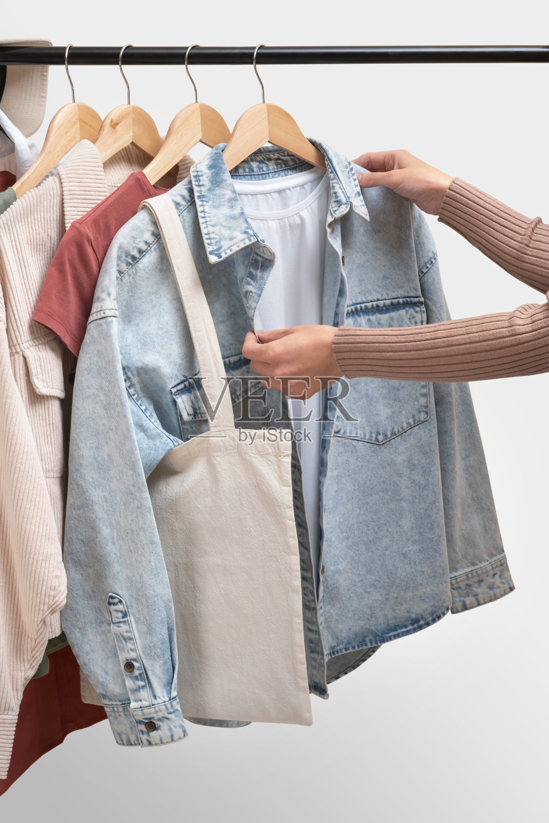 时装设计师在陈列室的栏杆上挑选衣服。基本的女性服装和环保袋的白色背景。女人在架子上收集衣服。春夏时尚潮流概念。以时尚女装为栏杆,服装零售理念照片摄影图片