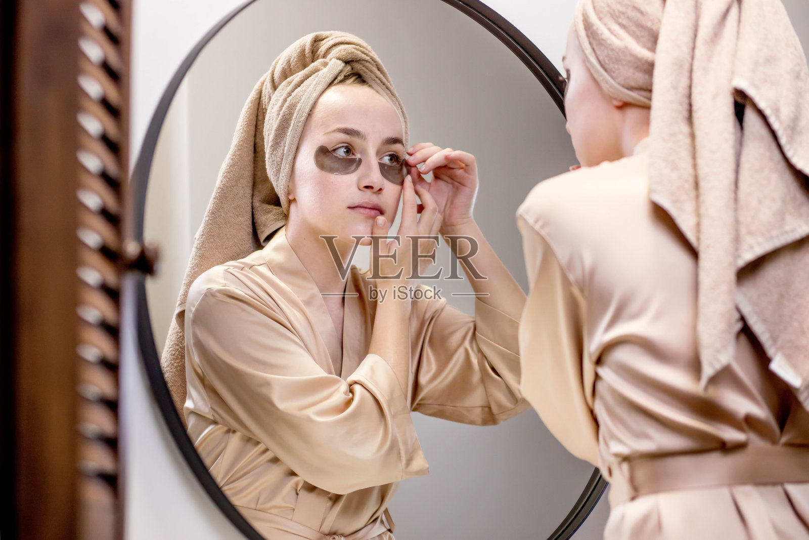 年轻女子在米色毛巾和浴袍,照顾皮肤下的眼睛与补丁。照片摄影图片