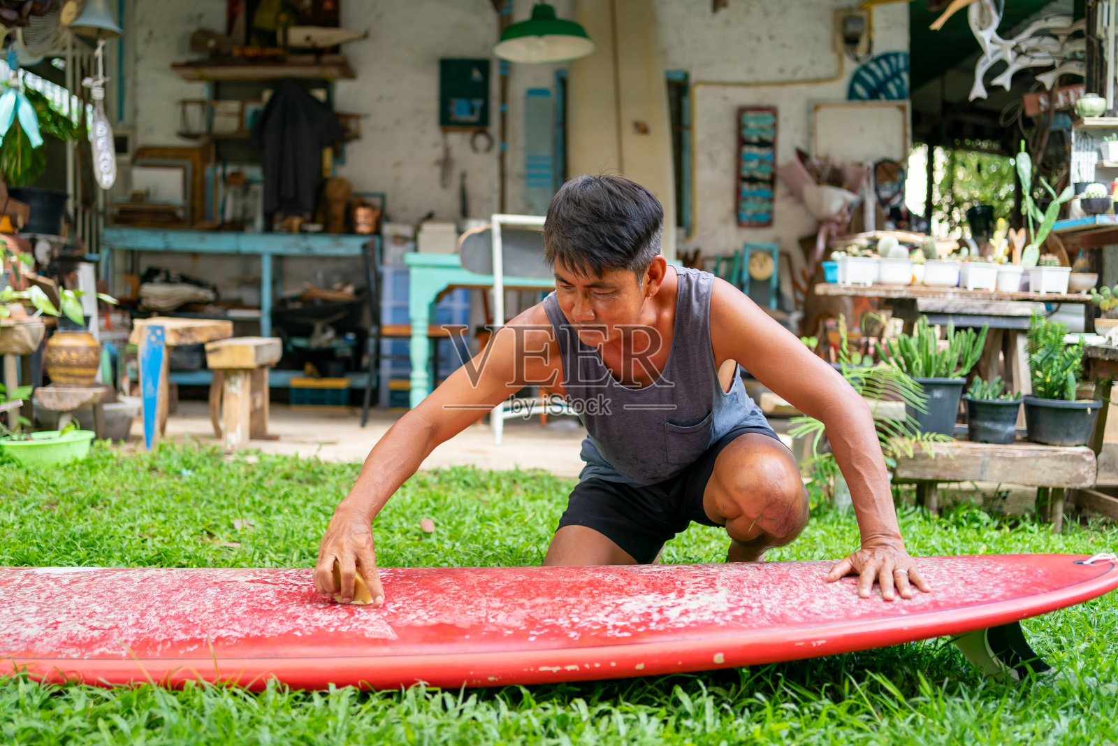 亚洲老人在家里给冲浪板表面打蜡。照片摄影图片
