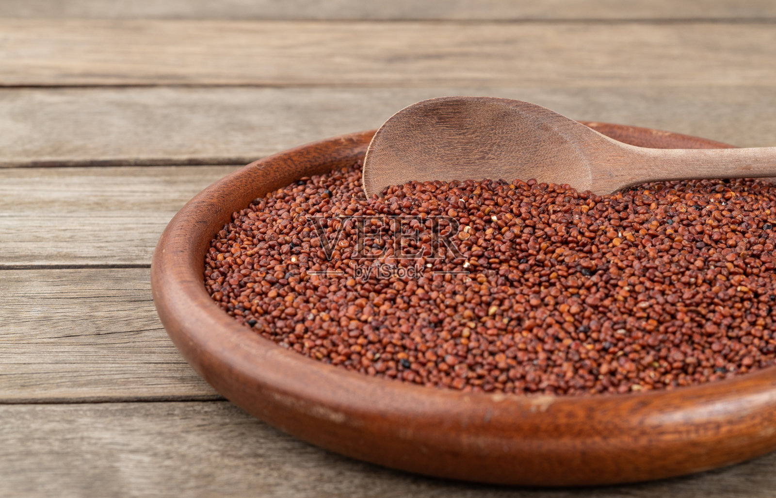 狭窄的焦点,生的红色藜麦放在盘子里,放在木桌上照片摄影图片