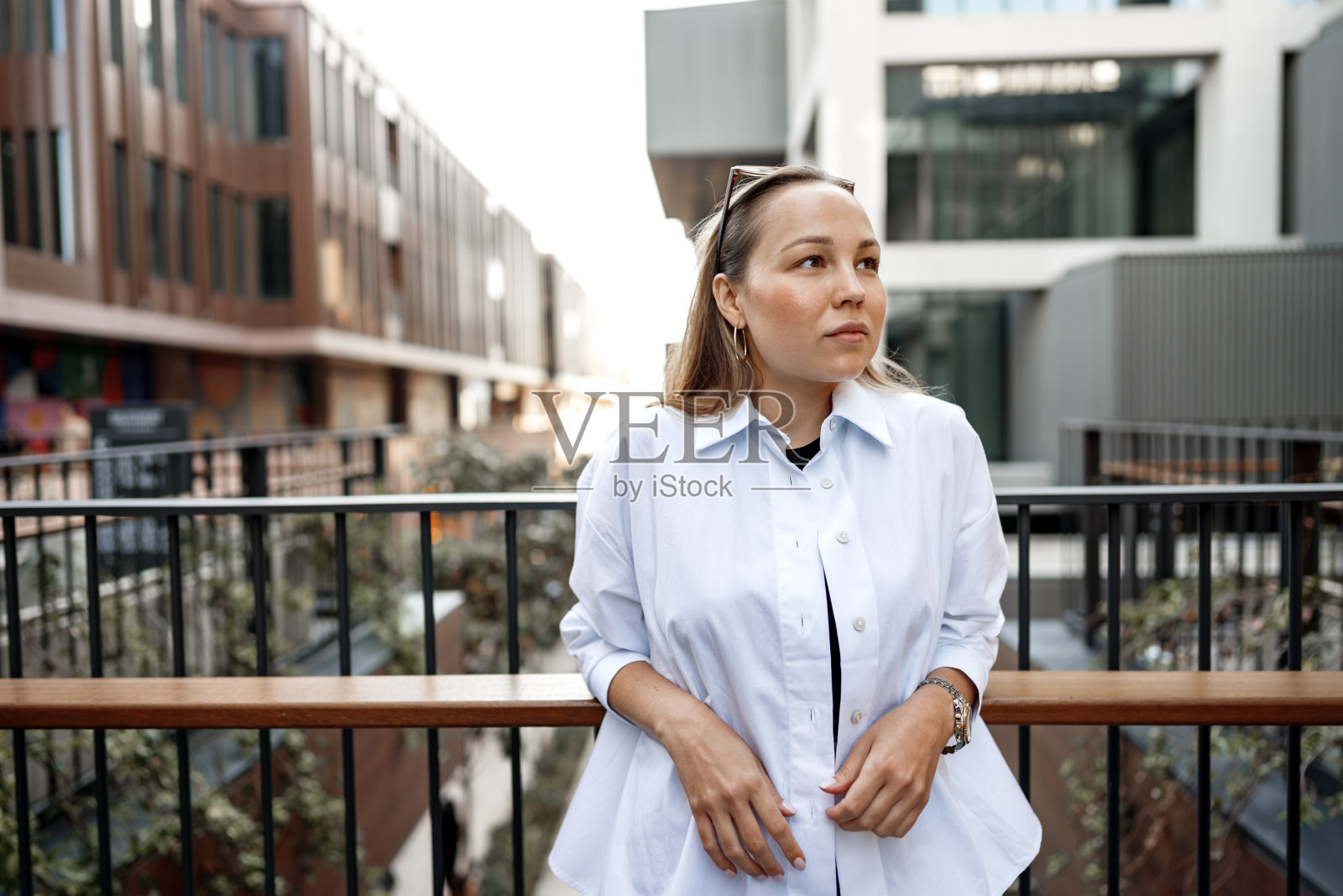 年轻的办公室女性站在阳台上欣赏城市景色的肖像照片摄影图片