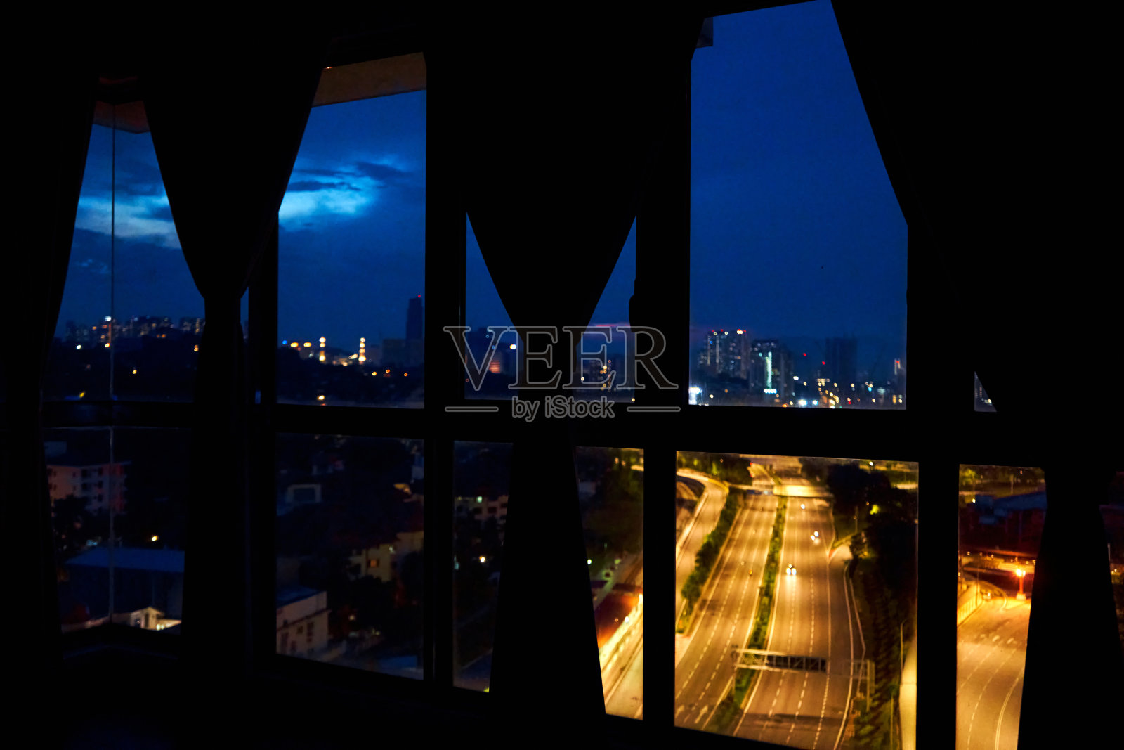 在通往大都市的多车道高速公路上,公寓窗外的夜景。夜景。照片摄影图片