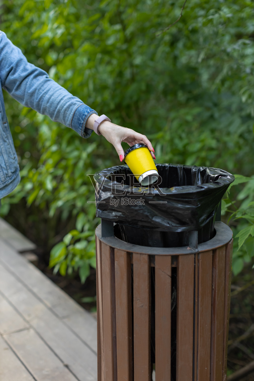 一个女人的手把一个纸杯扔进了垃圾桶照片摄影图片