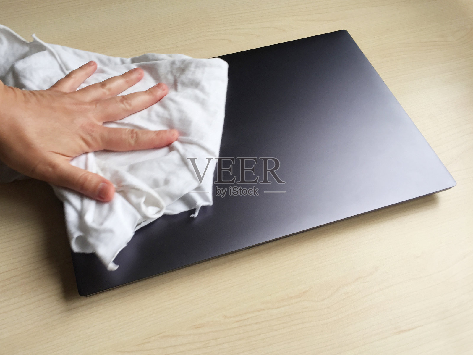 用抹布清理桌上的笔记本电脑,除尘照片摄影图片