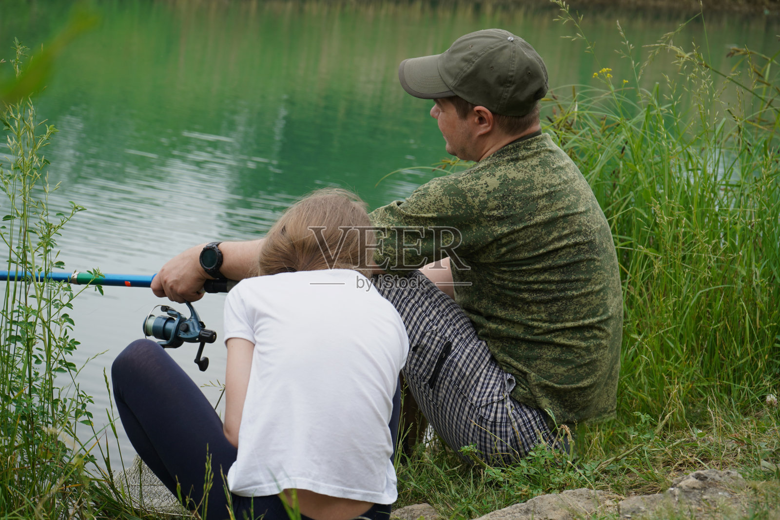 幸福的家庭,女儿和父亲在多云的天气在河岸钓鱼。照片摄影图片