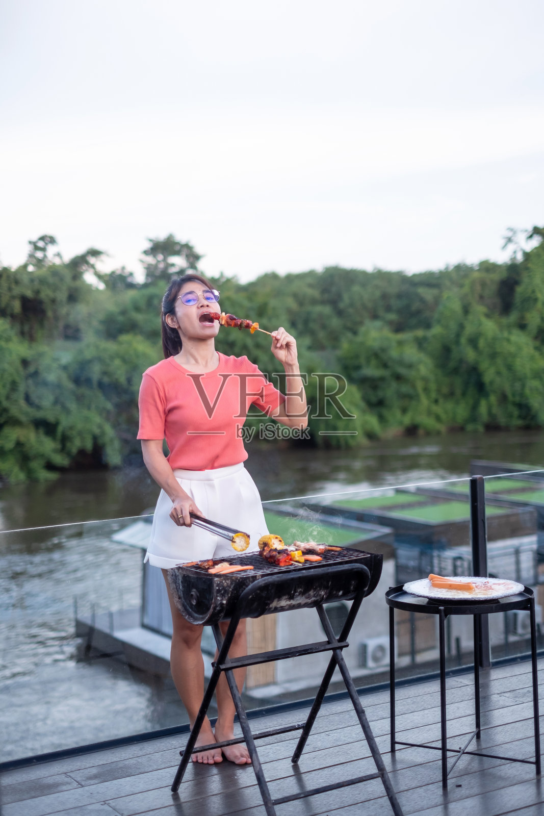 快乐的女人与美味的烤肉和户外烧烤。烧烤,聚会,生活方式和野餐的概念照片摄影图片