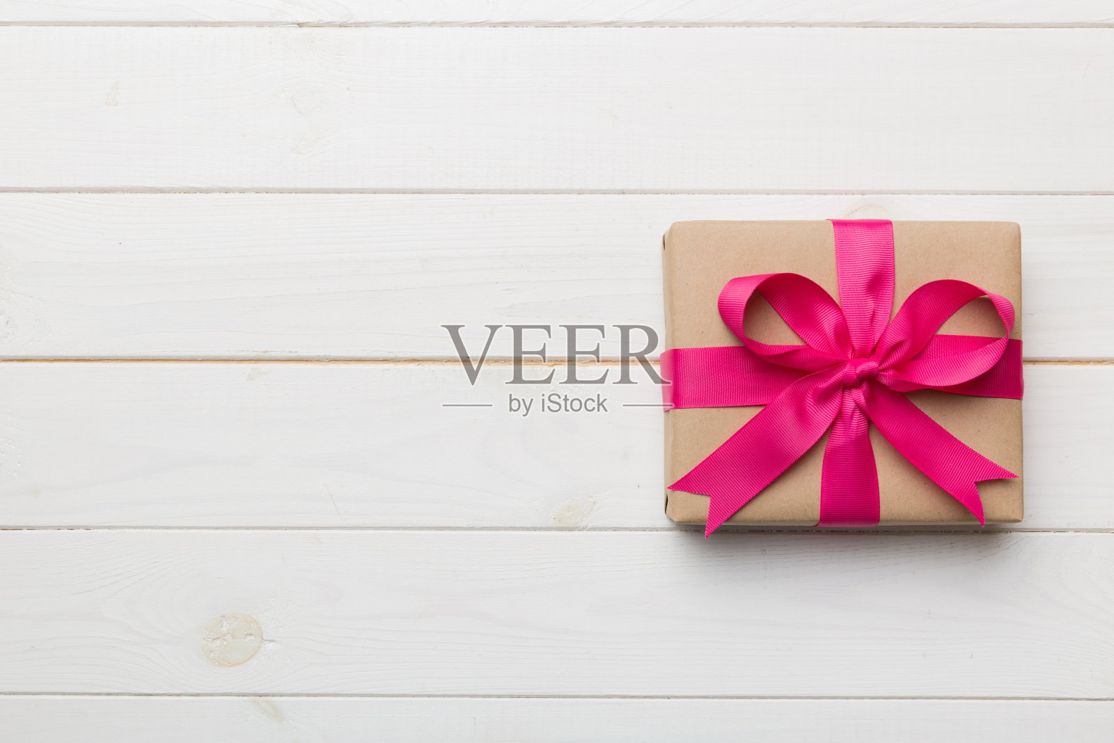 节日礼盒包装牛皮纸与彩色蝴蝶结在桌子的背景。俯视图,平铺,复制空间照片摄影图片