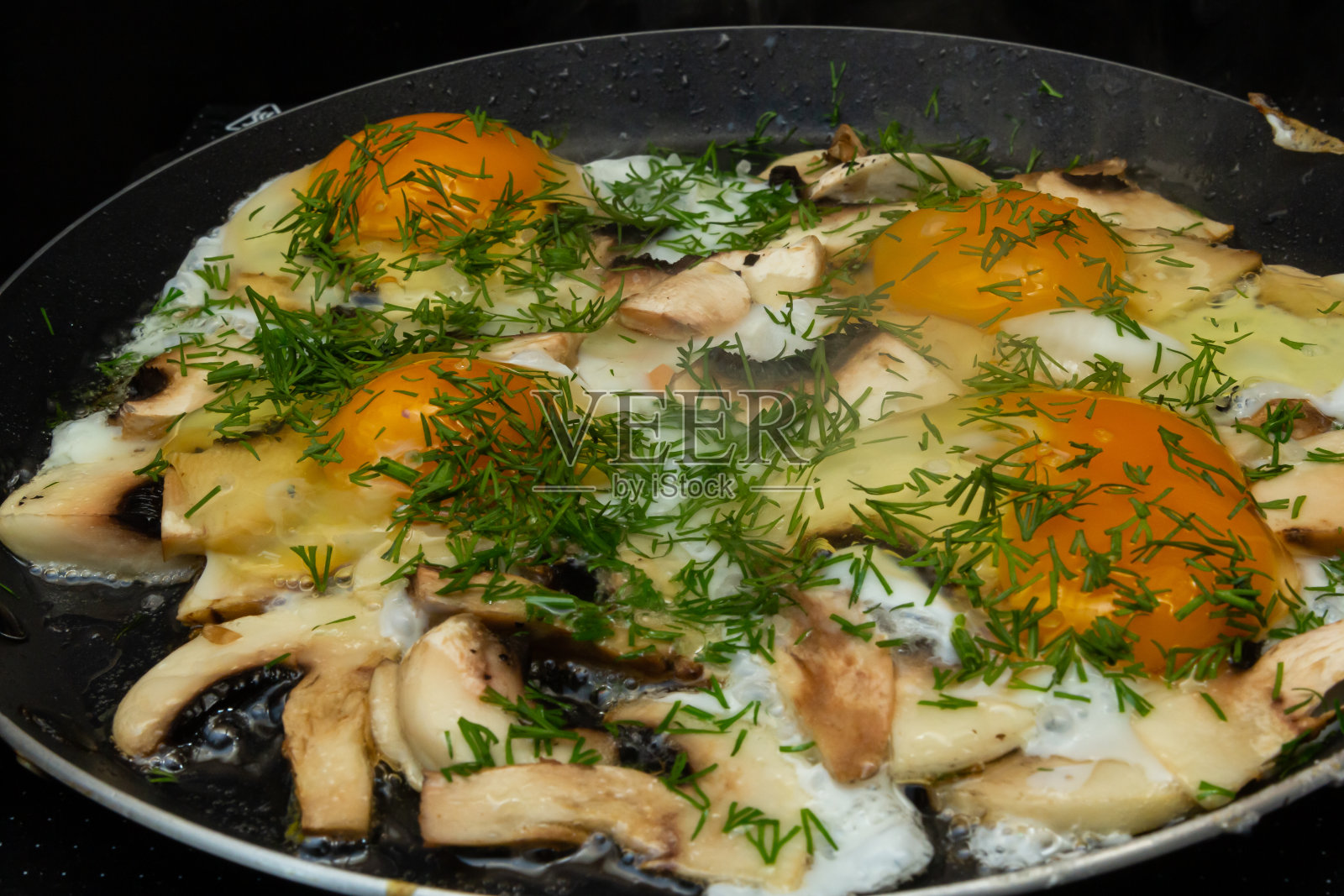 在平底锅里煎蘑菇和鸡蛋。做早餐的过程近距离照片摄影图片