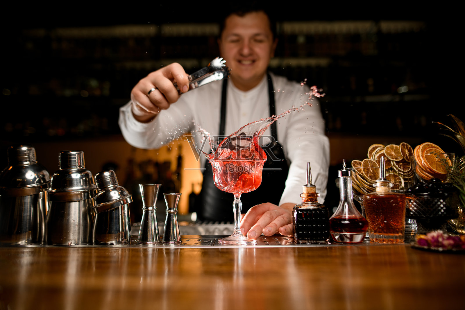 酒吧柜台上的美景,各种酒吧设备和飞溅饮料的高脚杯照片摄影图片