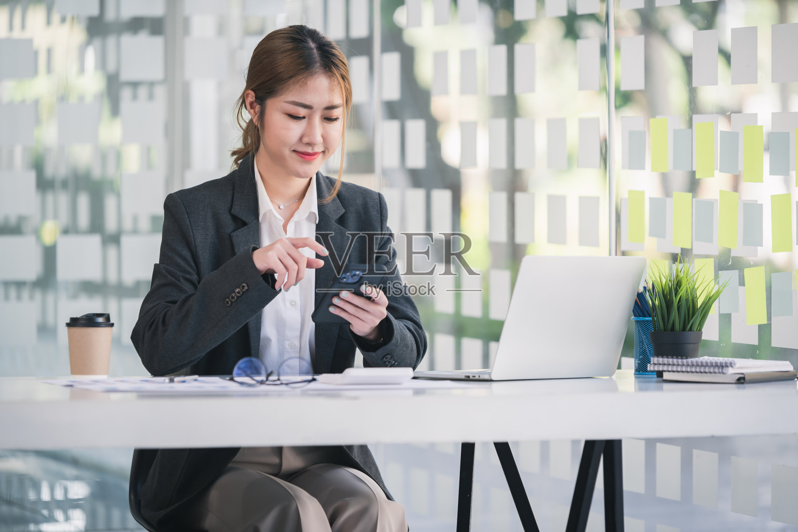 亚洲女孩的肖像在现代办公室用智能手机与顾客交谈照片摄影图片