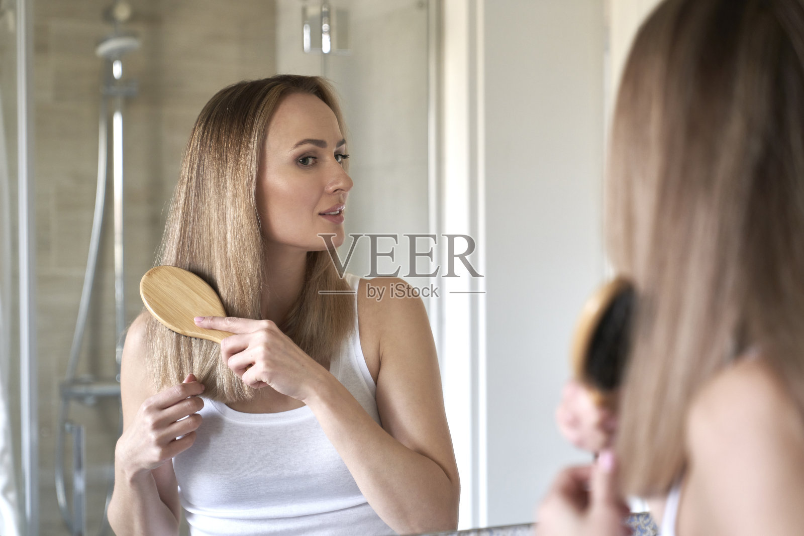 年轻的白人女性在浴室里梳头发照片摄影图片