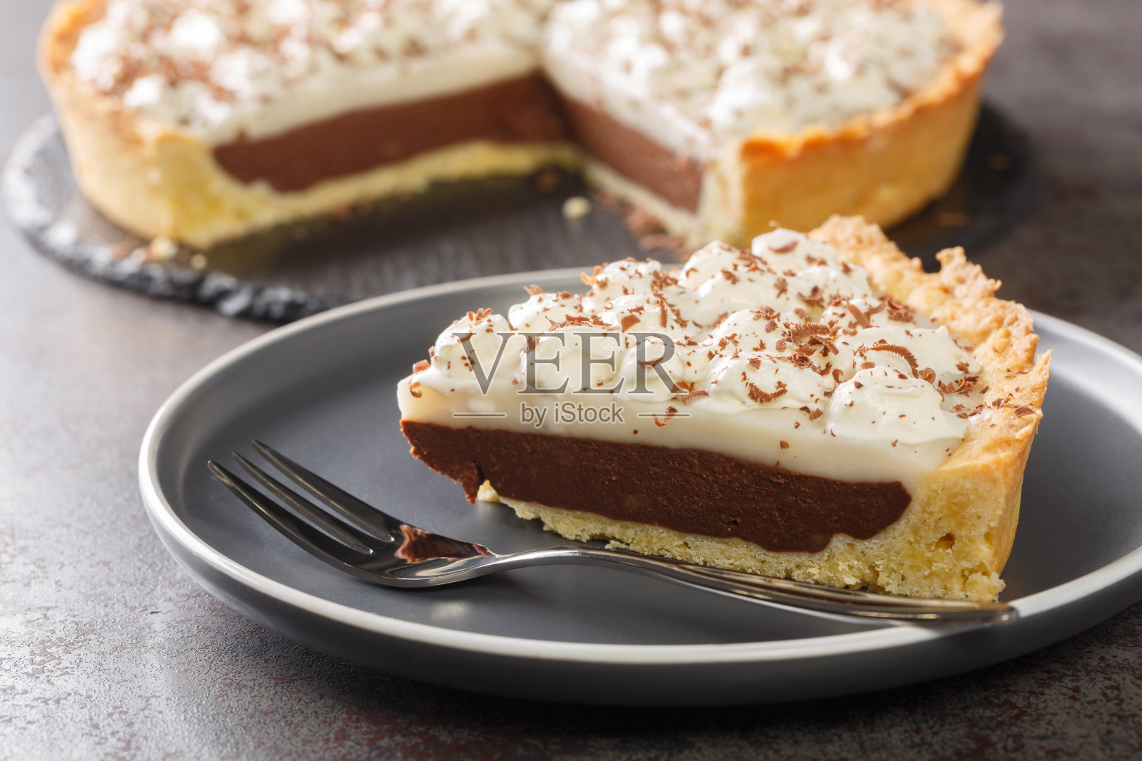 椰子荷皮亚和巧克力派,上面淋上鲜奶油。水平照片摄影图片