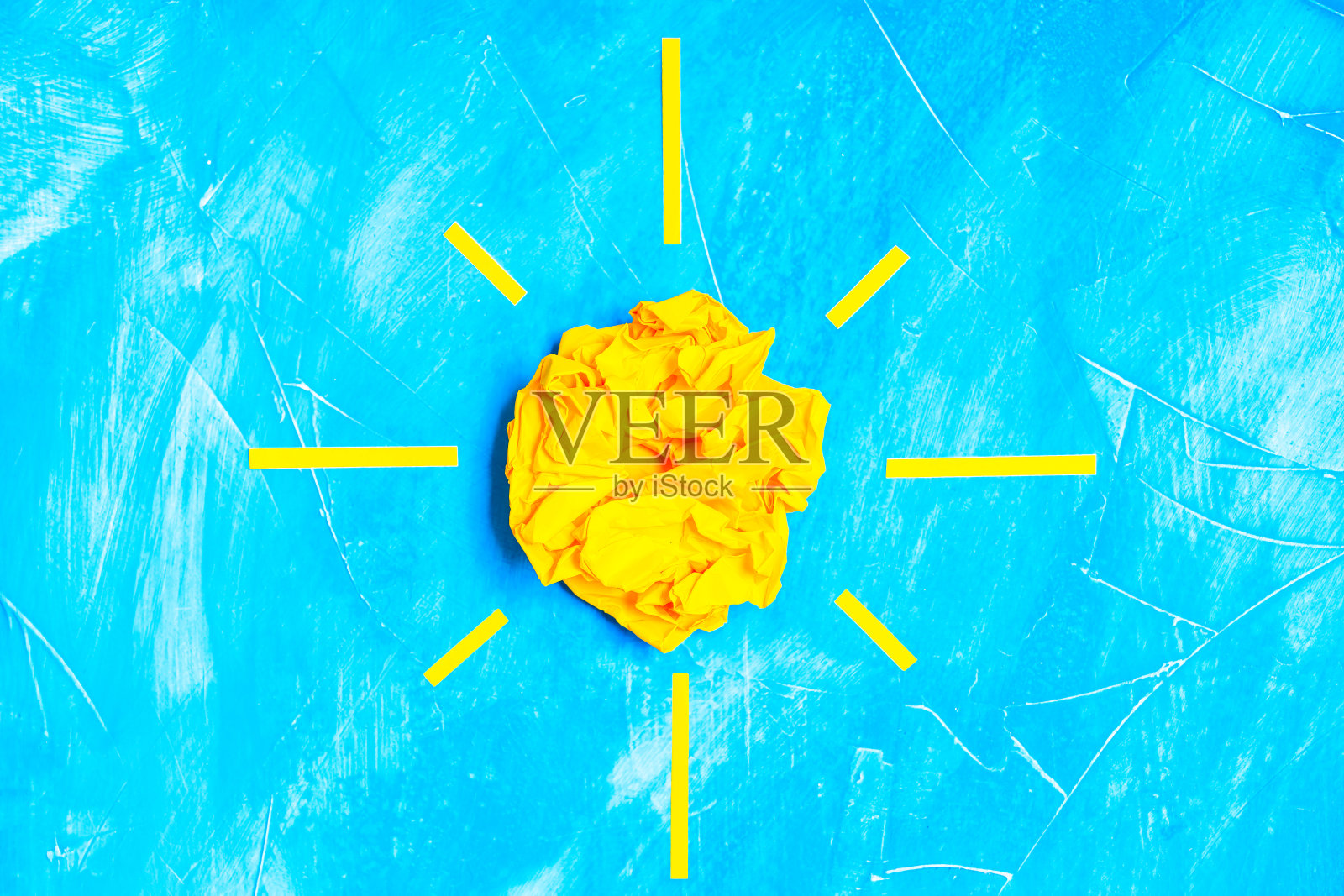 太阳符号由一个皱巴巴的纸球在蓝色照片摄影图片