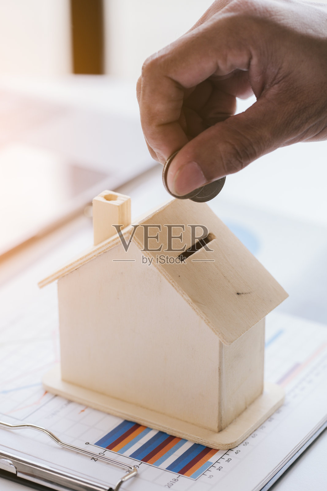 近距离的手是扔一个硬币到房子模型保存盒与文件和笔记本电脑。照片摄影图片