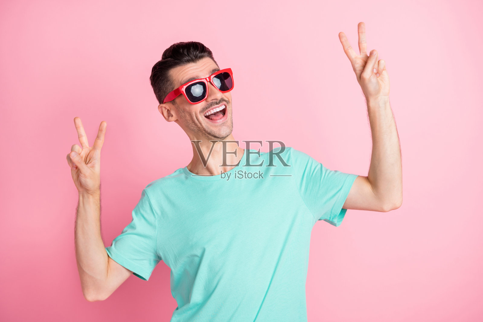 年轻兴奋的男子的照片快乐积极的微笑显示和平冷静的v字孤立在粉红色的背景照片摄影图片